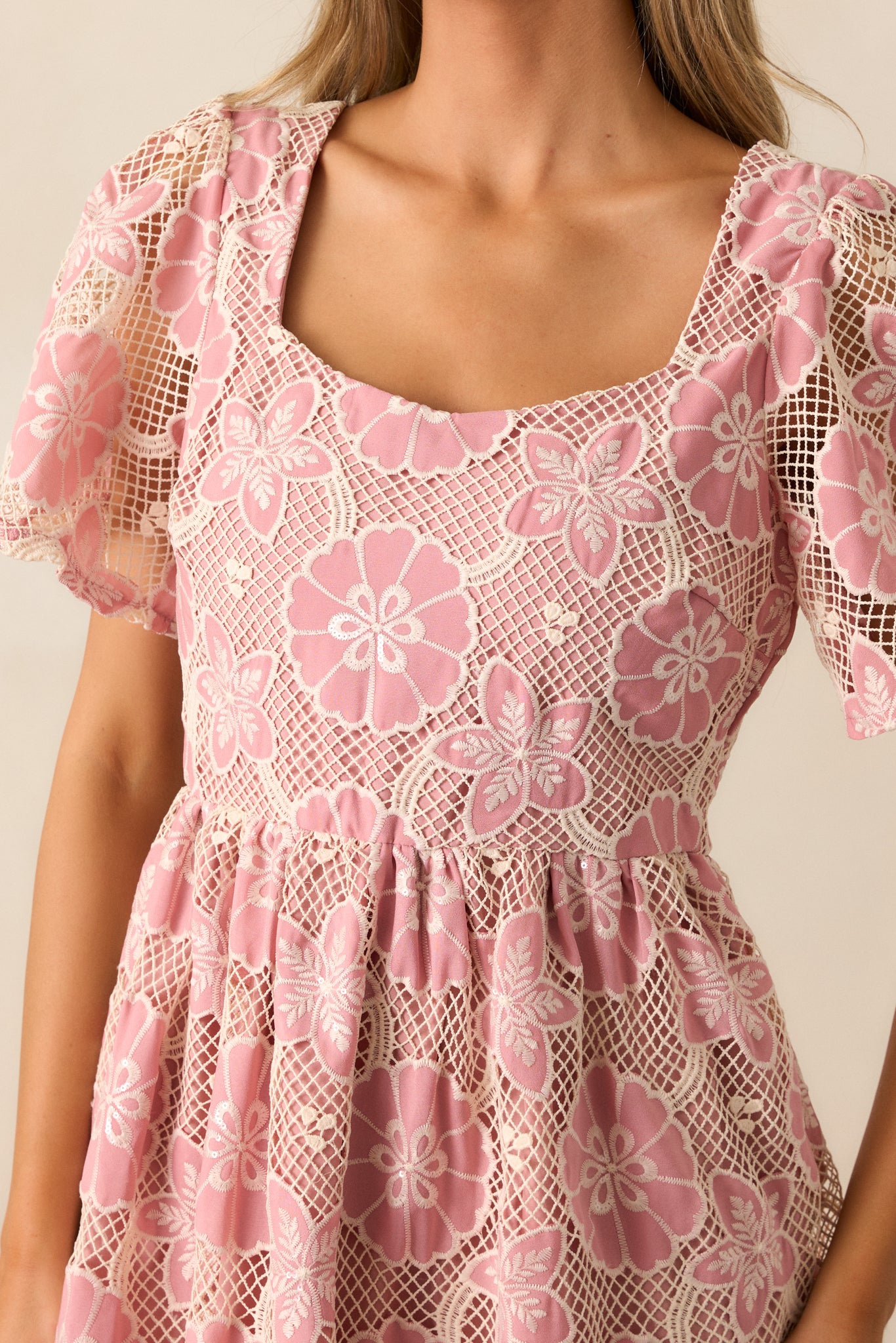 A close-up of the embroidered floral design on the bodice, with intricate stitching visible, and a glimpse of the sheer, embroidered fabric of the short sleeves.