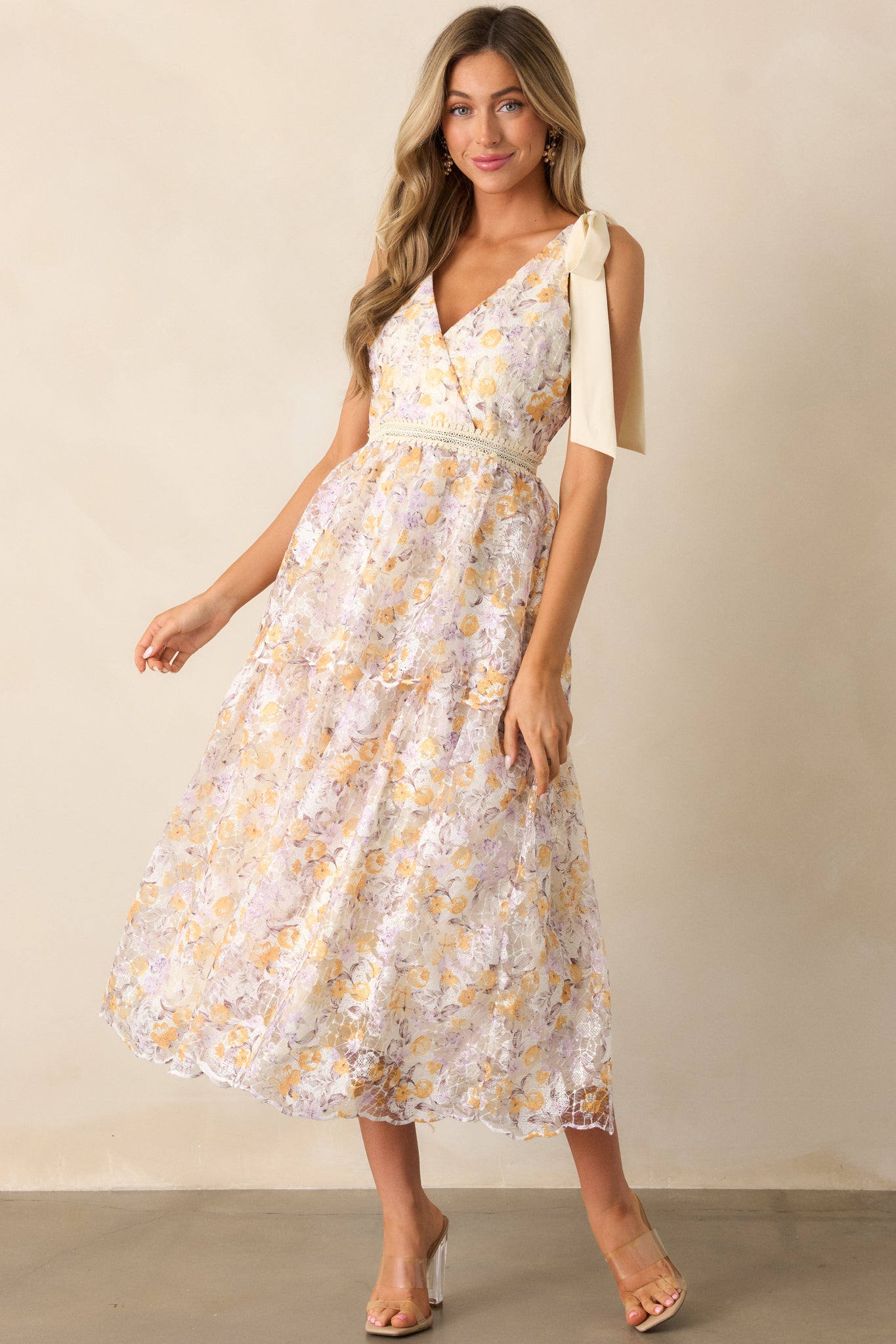 This apricot midi dress highlights its embroidered waistband, flowing skirt, and intricate floral details.