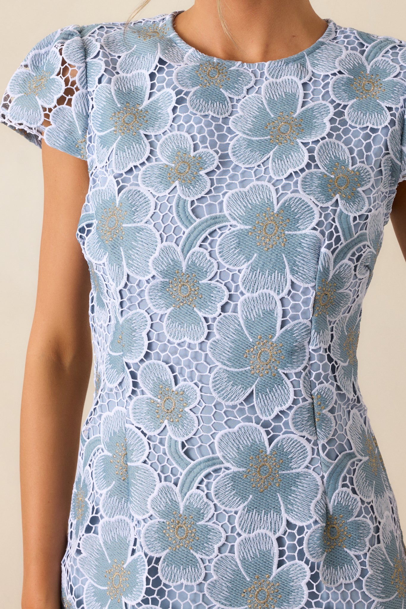 A close-up shot of the floral embroidery, highlighting its vibrant colors and precise stitching against the sky blue background.