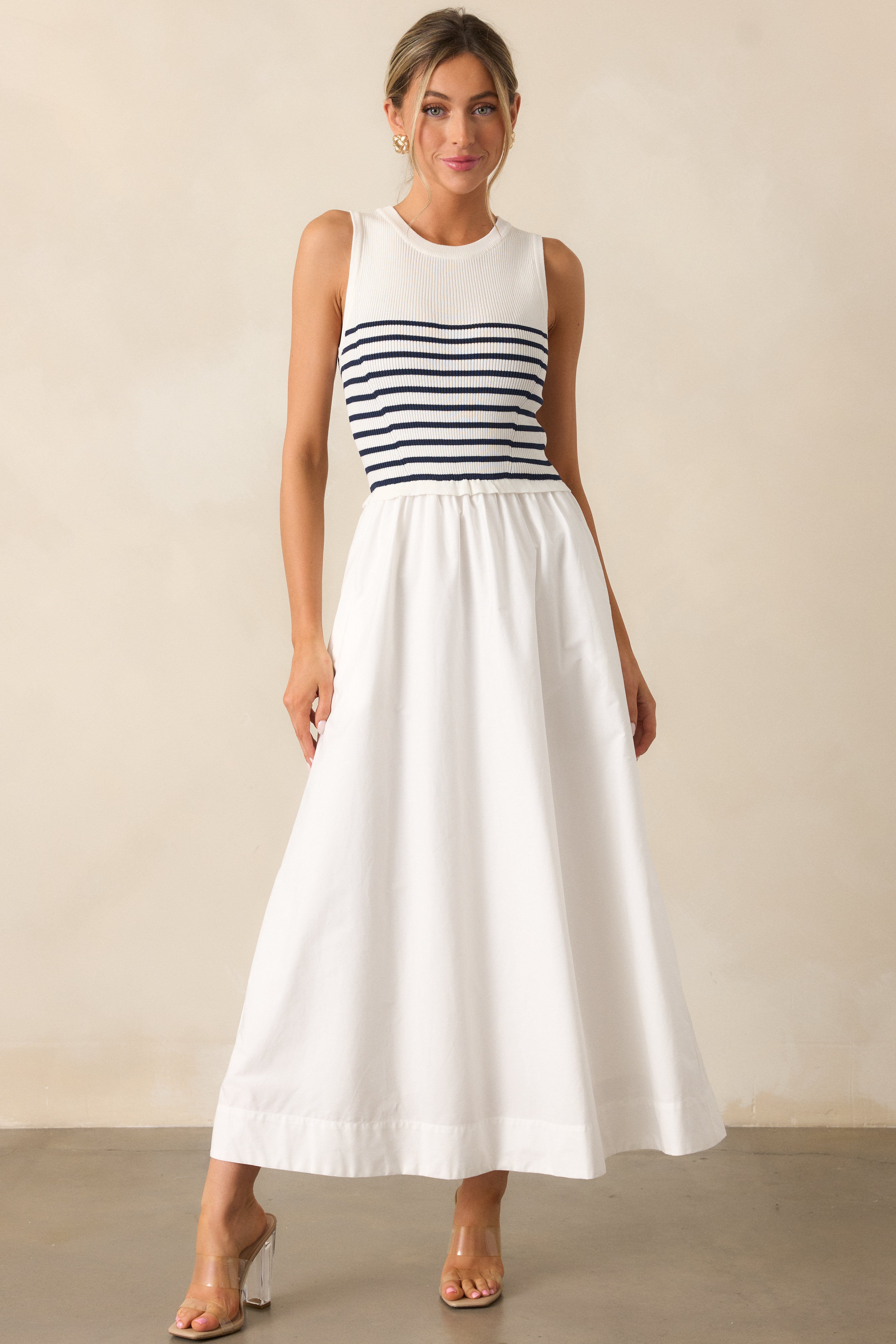 Full view of a white stripe dress featuring two functional pockets, a round neckline, and a fitted bodice.