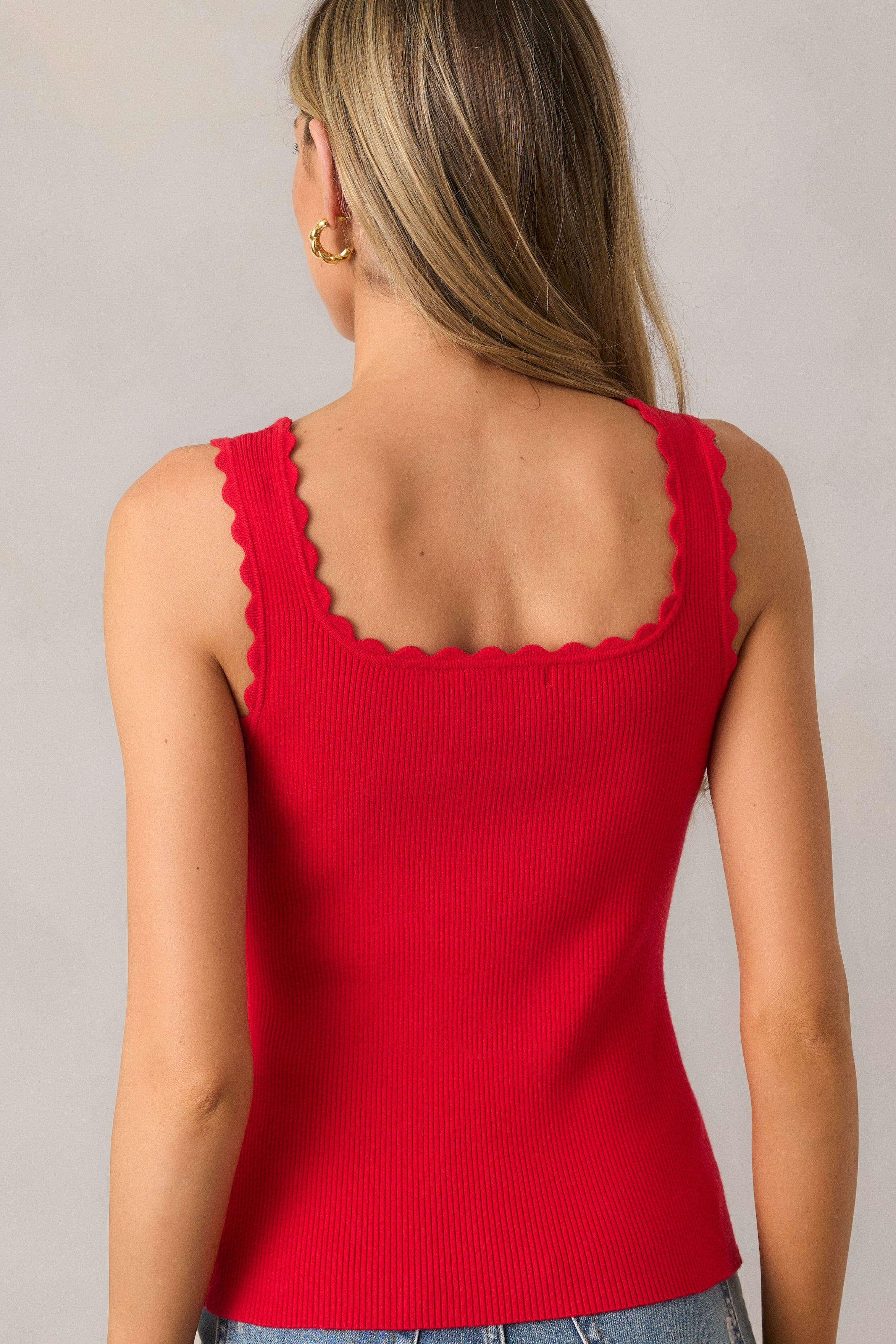 The red tank top from behind, showcasing the simple yet stylish design, highlighting the ribbed fabric and sleeveless cut, with the scalloped hemline adding a subtle flair.