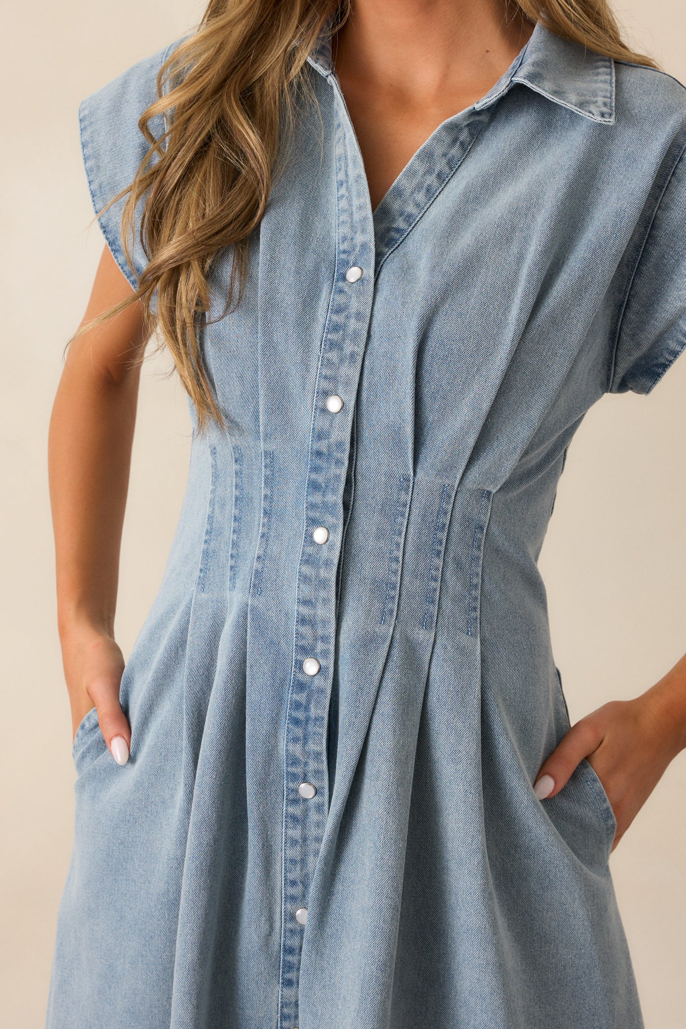 Close-up of the button front on the light wash denim dress, featuring pearlized snap closures and functional pocket detail.