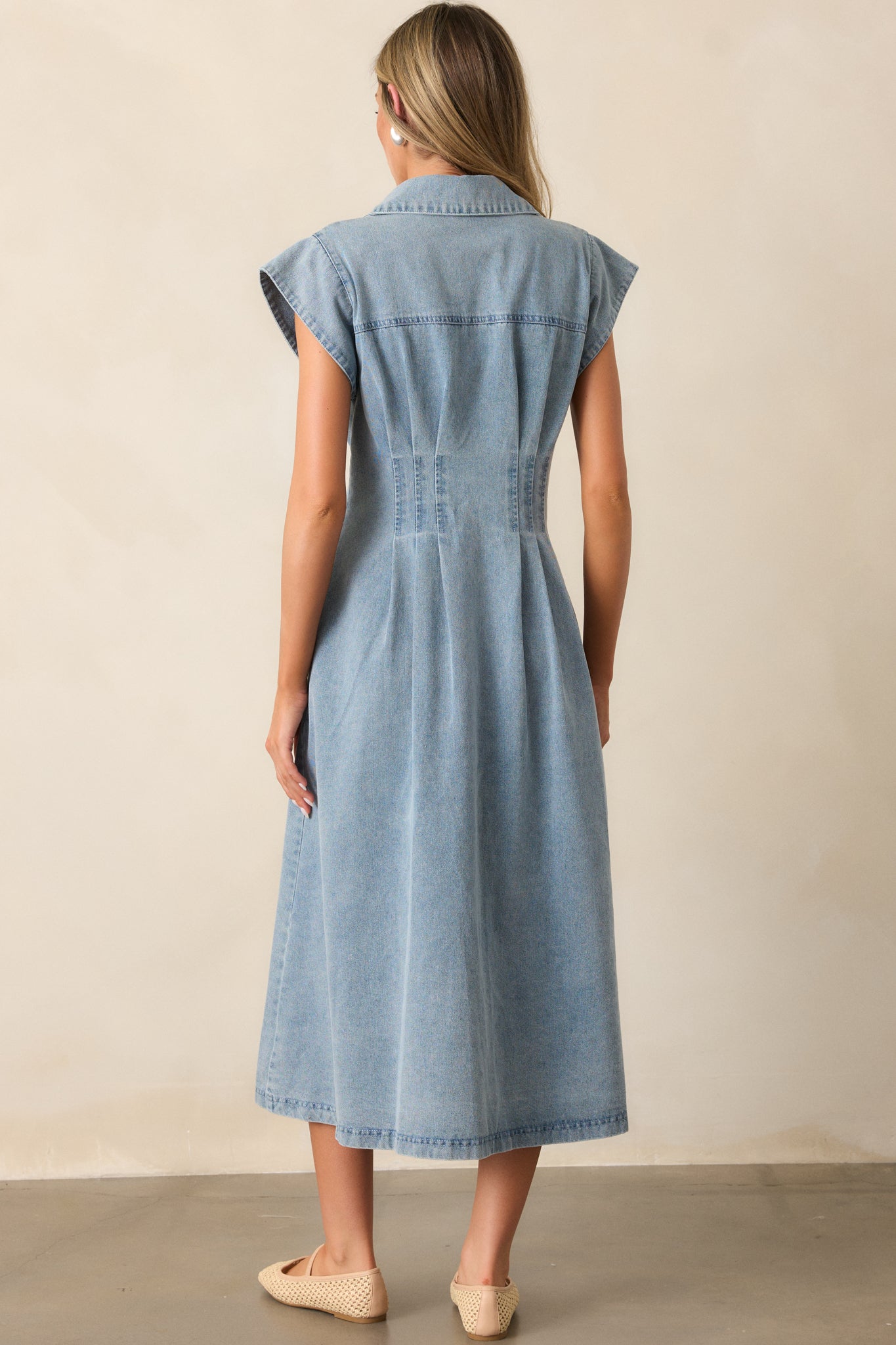 Back view of the light wash dress showing its pleated waist design and cap sleeve details.