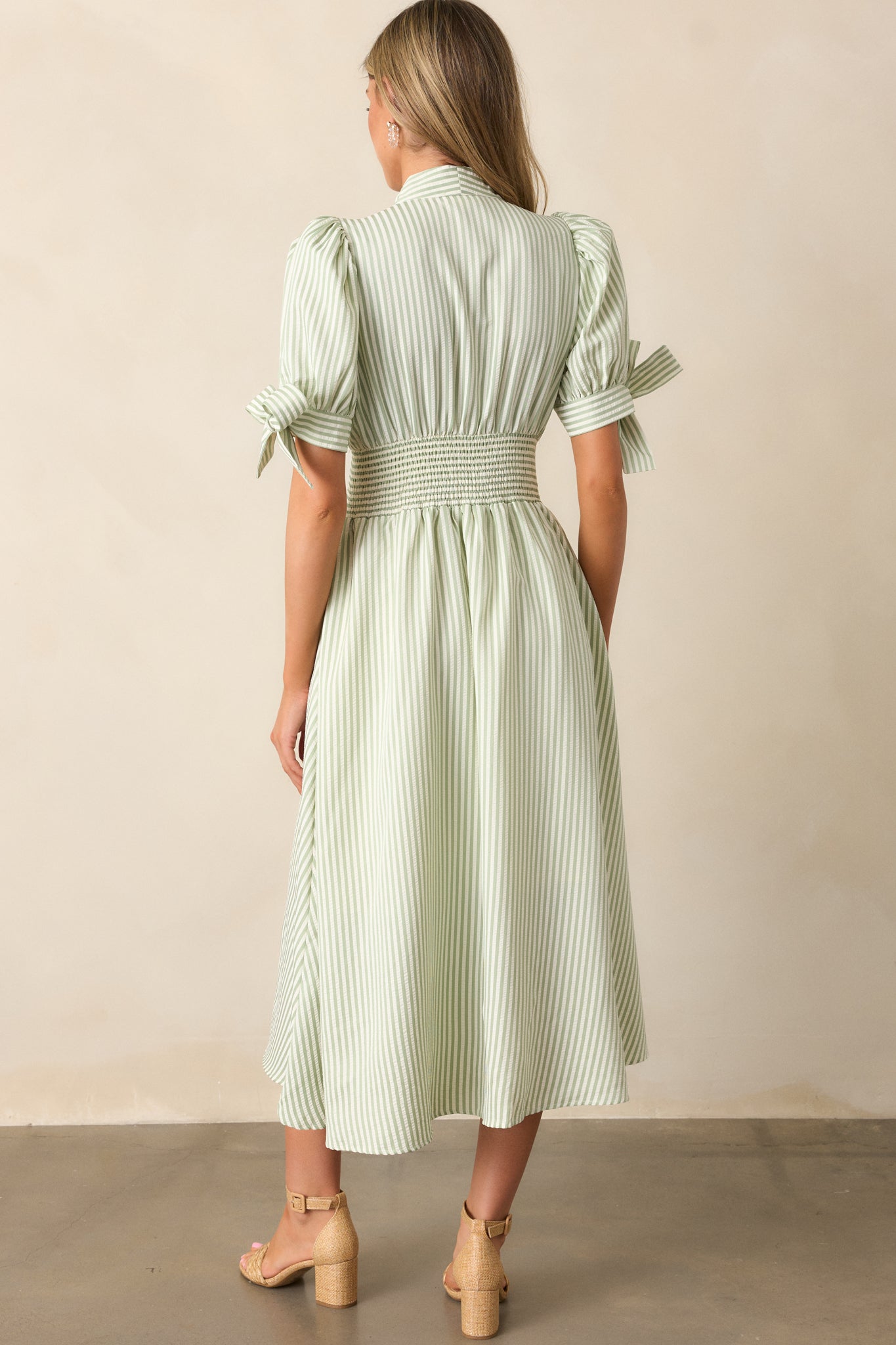 Back view of the green stripe dress, highlighting the fitted smocked waist and flowing skirt, with a seamless stripe pattern and long sleeves.