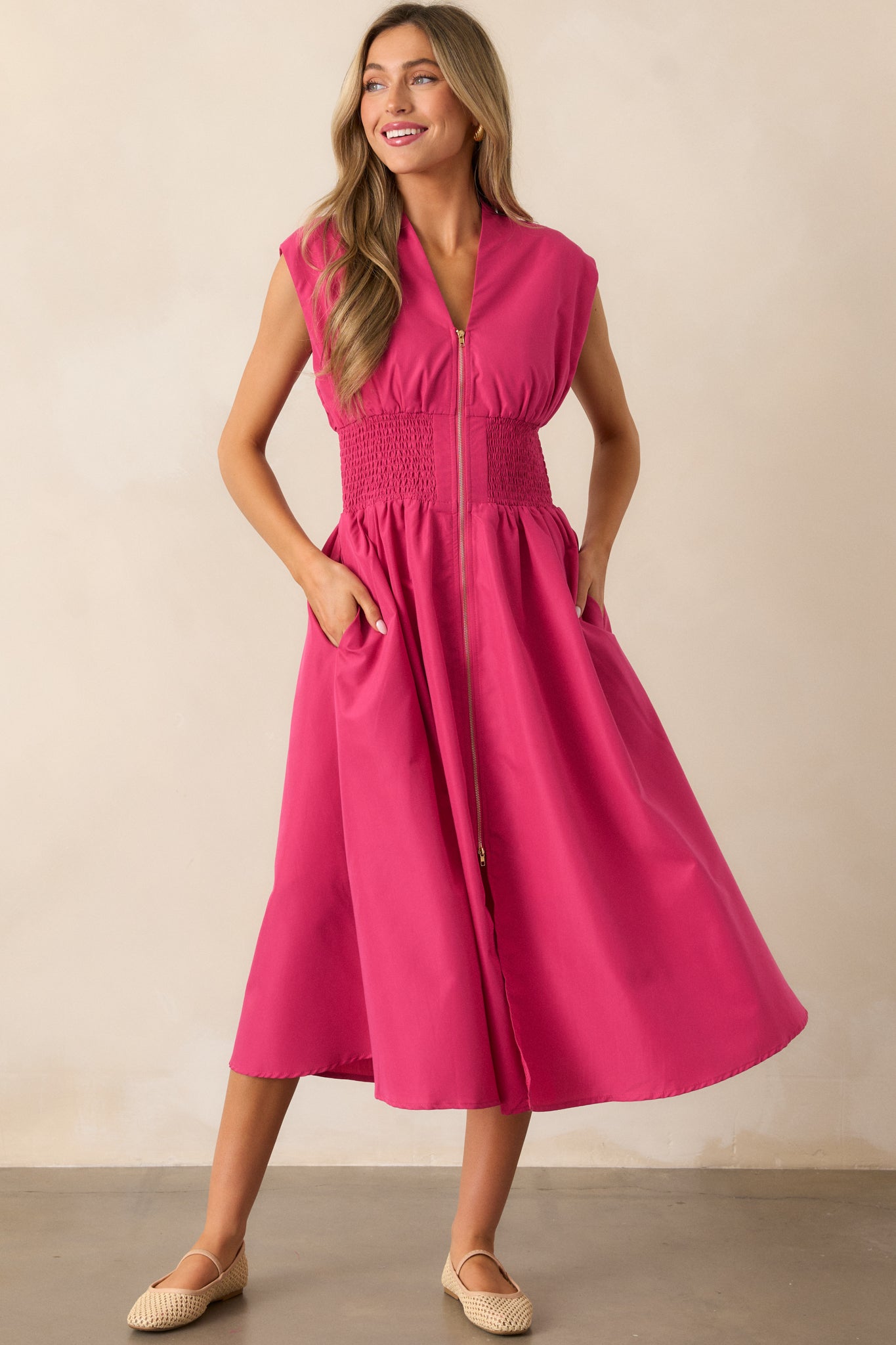 The magenta midi dress with a smocked waist, functional hip pockets, and a front slit, emphasizing its flattering silhouette.