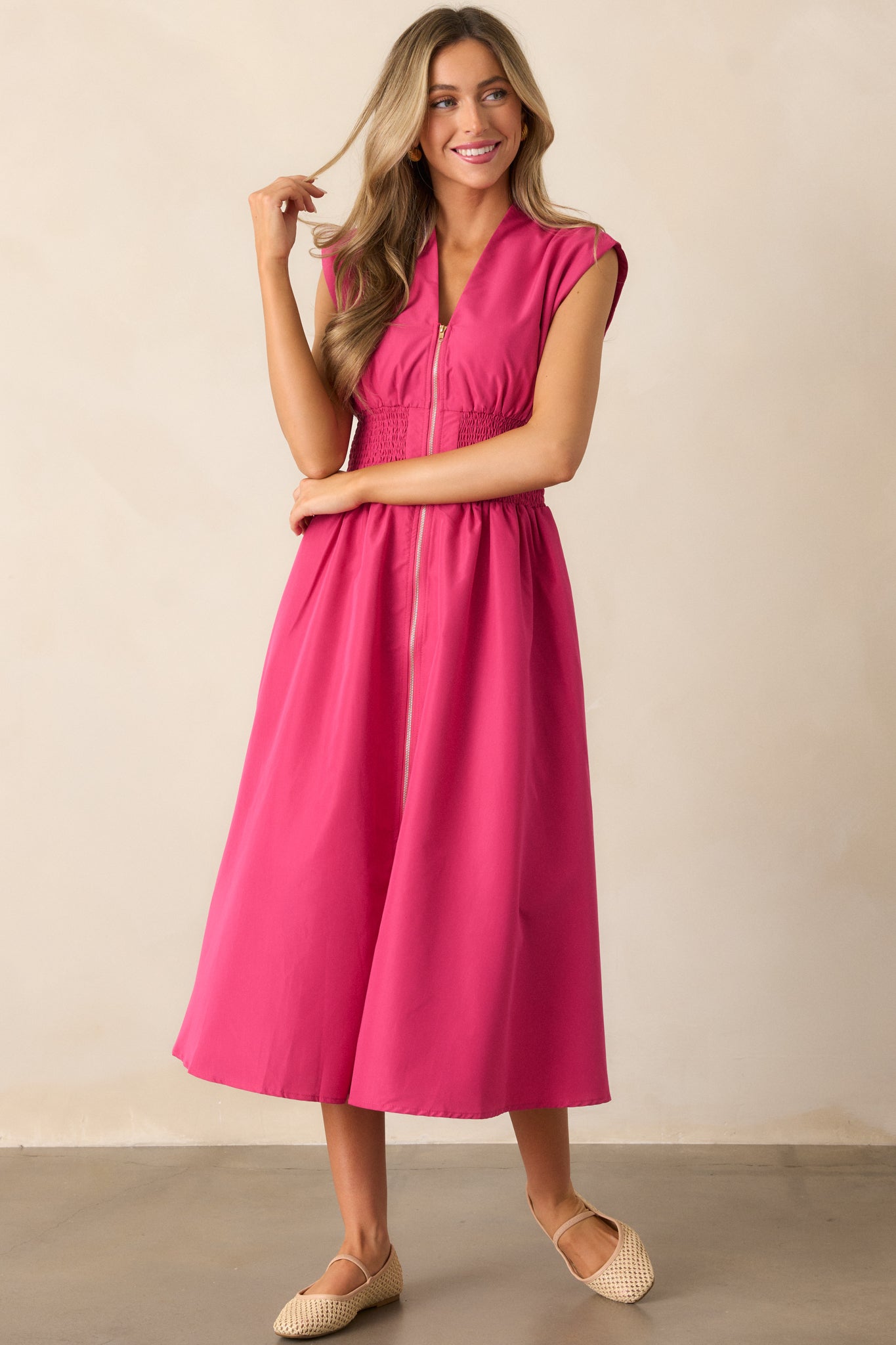 Another front shot of the magenta midi dress, showing off its front slit, smocked waist, and hip pockets.