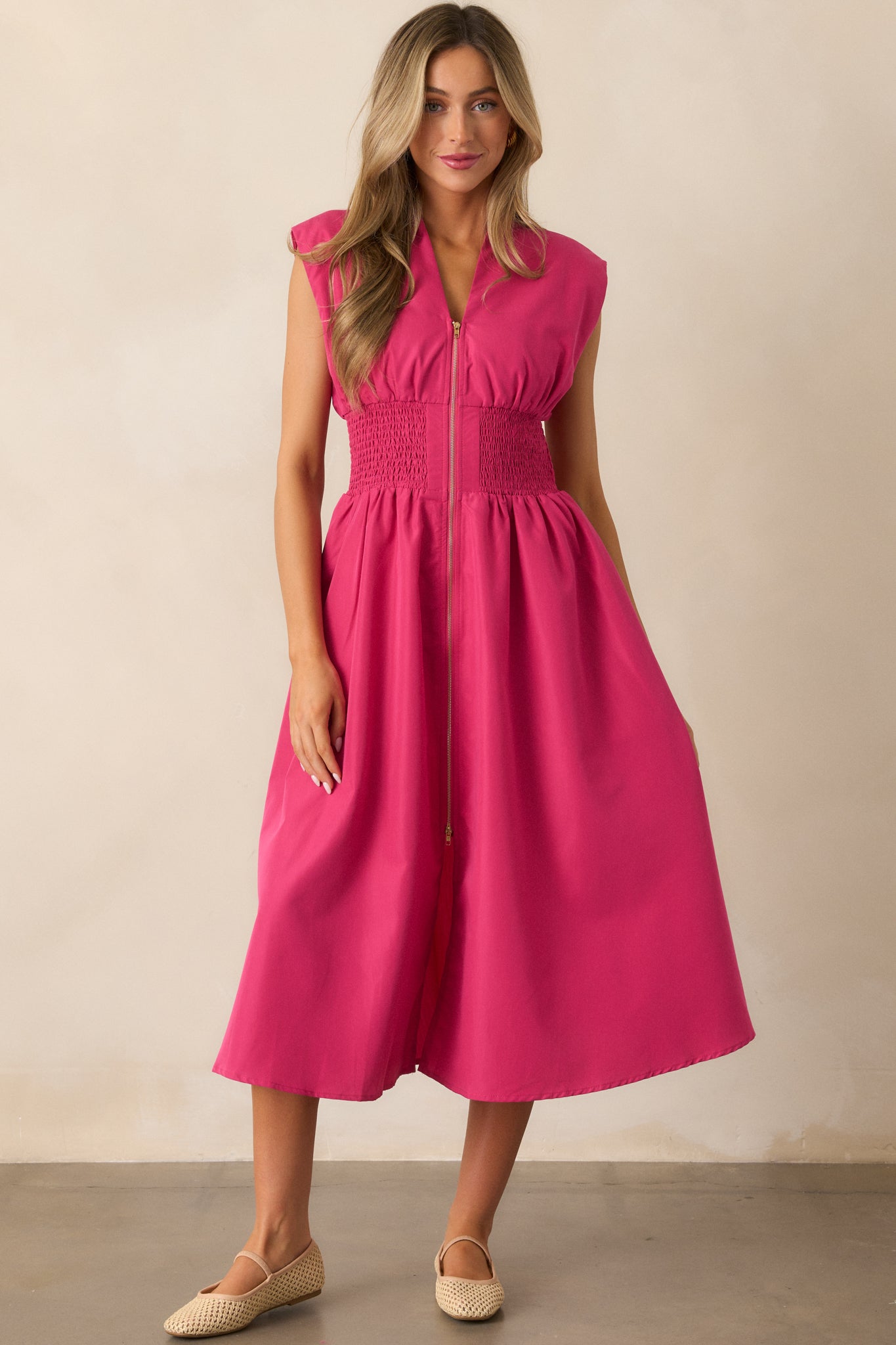 A full view of the magenta midi dress showcasing its v-neckline, padded shoulders, and capped sleeves, with a functional zipper front and a front slit.