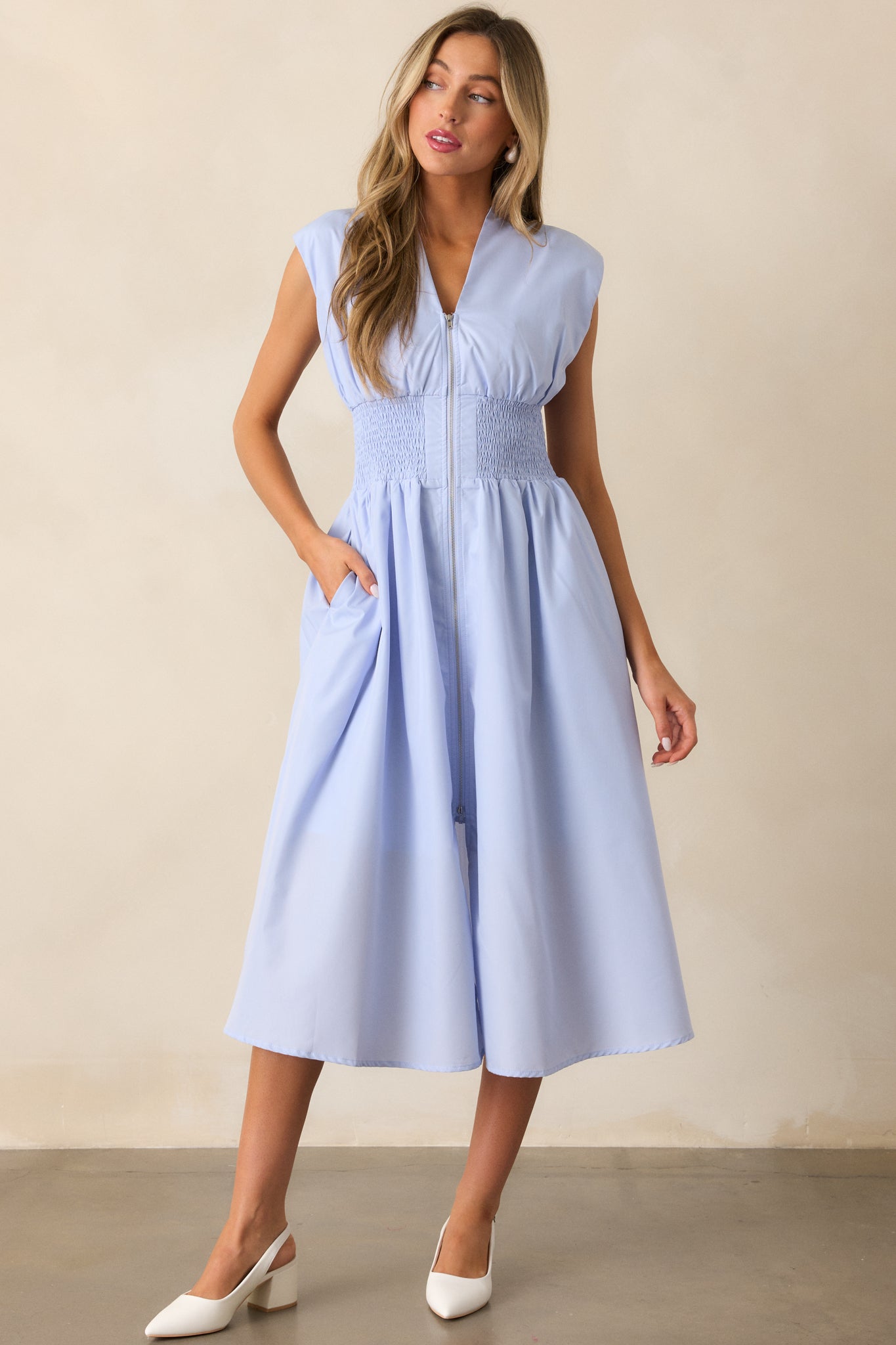 A baby blue midi dress featuring a v-neckline, padded shoulders, and capped sleeves, with a flattering smocked waist and front slit for added movement.