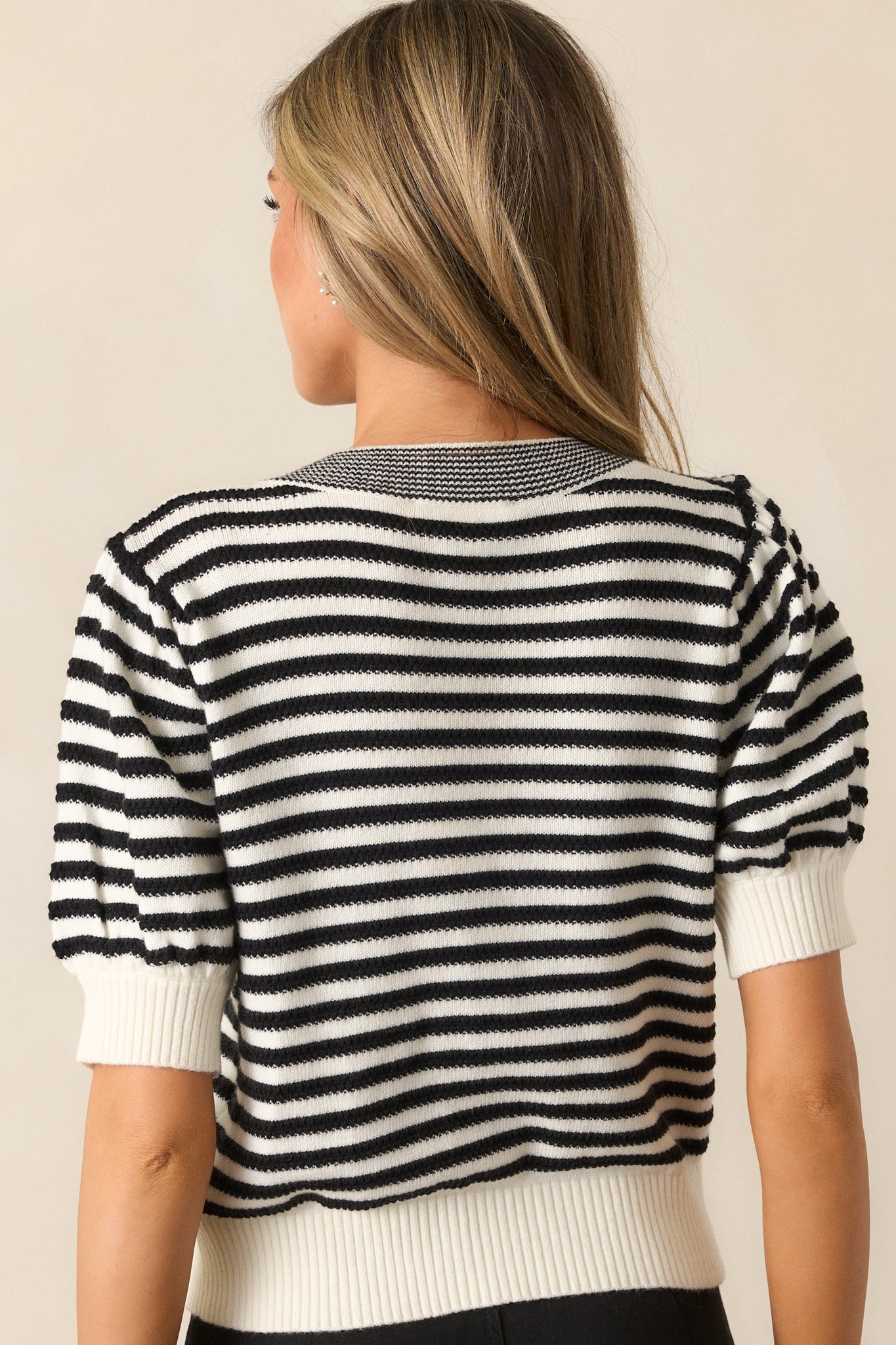 The back of the black top, displaying the continuation of the striped print and puff sleeve design with ribbed cuffs.