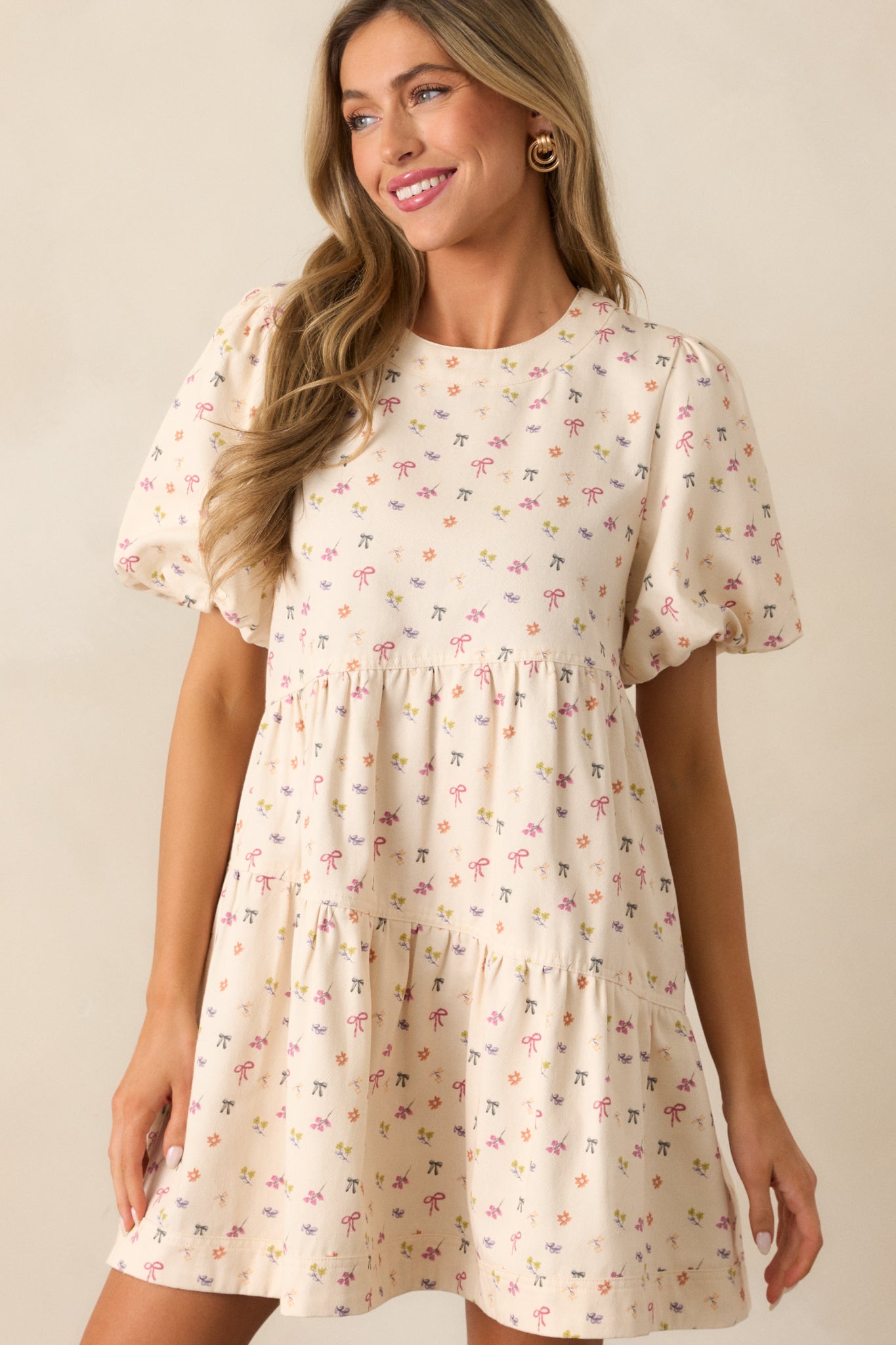 A cropped view of the ivory dress's rounded neckline and dainty bow, highlighting the intricate floral print.