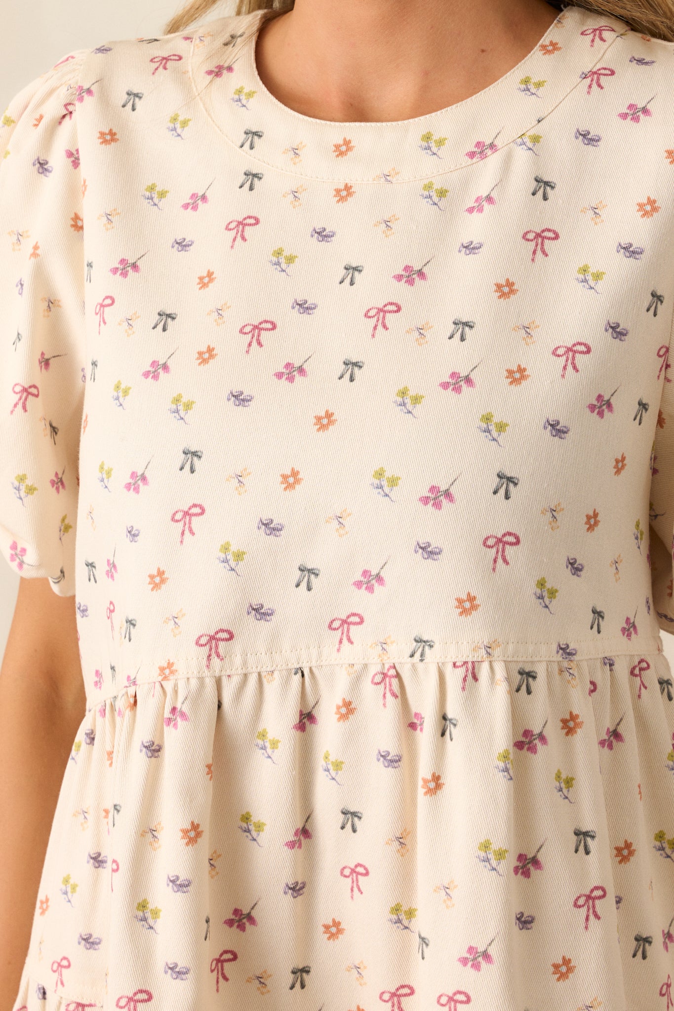 A close-up view of the ivory dress's dainty bow and floral print, emphasizing its delicate craftsmanship.