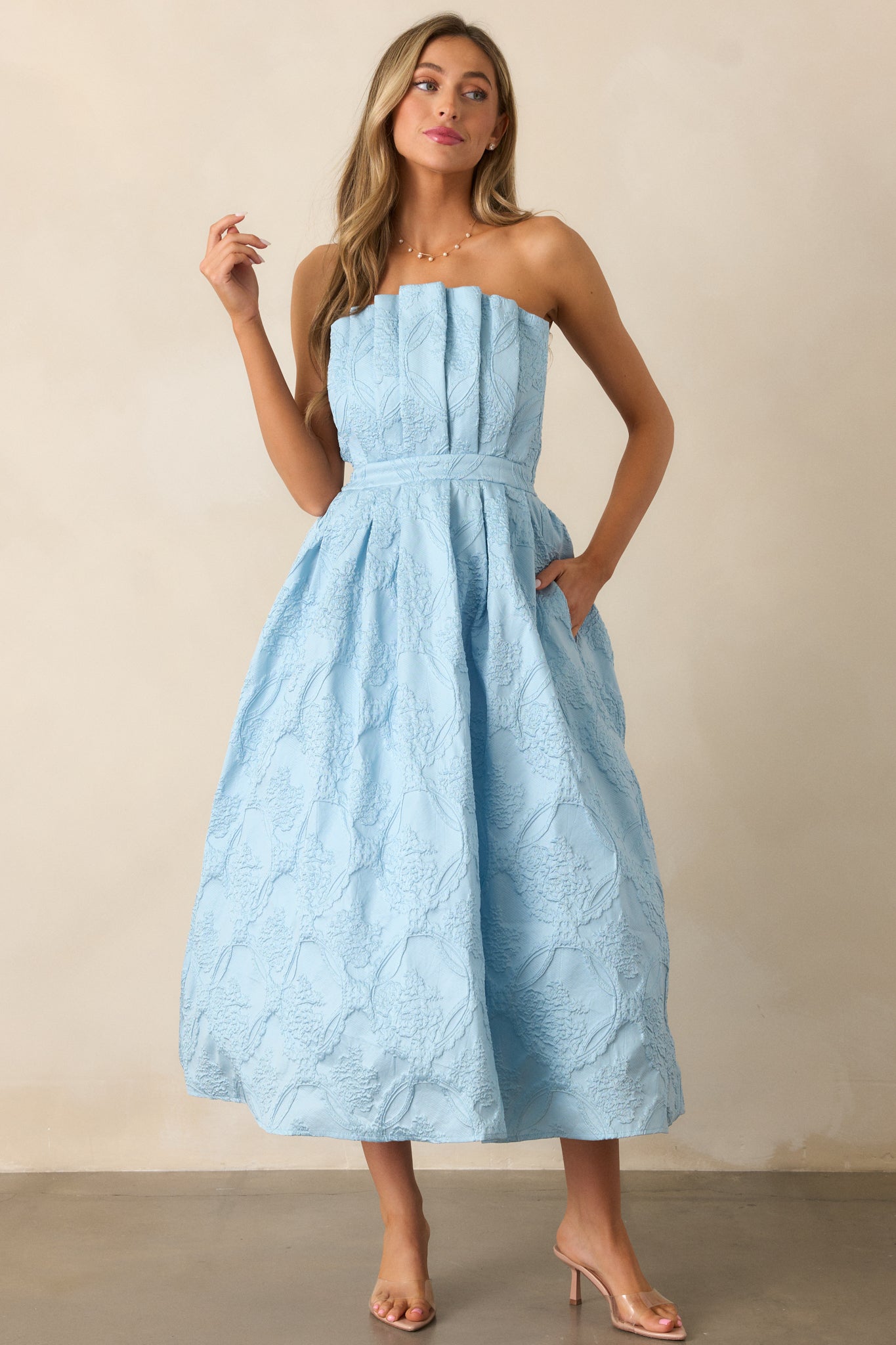  The sky blue midi dress showcasing functional hip pockets, a smocked back, and a discrete back zipper.