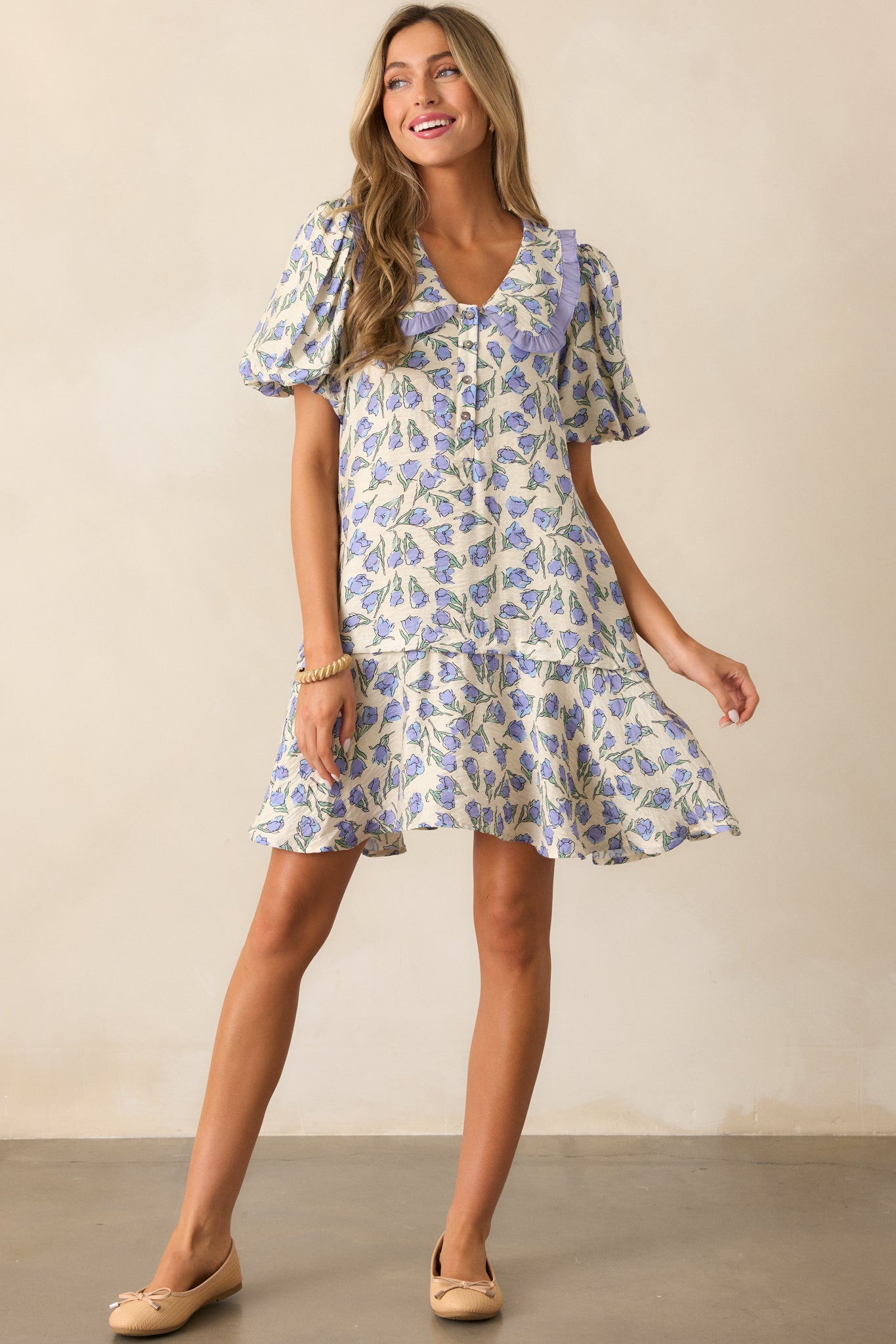 A full-length view of the periwinkle blue mini dress, highlighting its floral design and button detailing down the front.