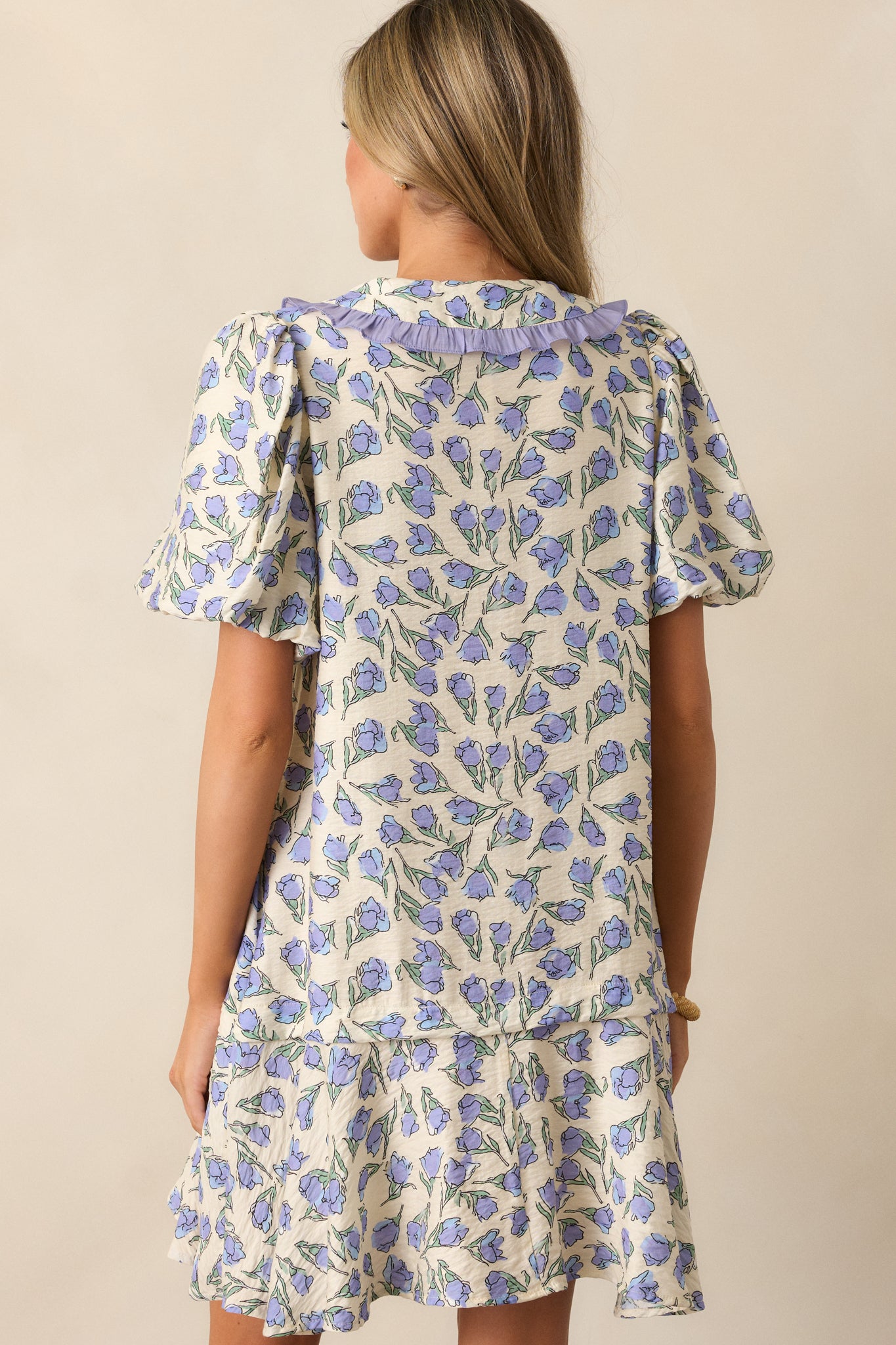 A back view of the periwinkle blue mini dress, highlighting its relaxed fit and seamless floral pattern.