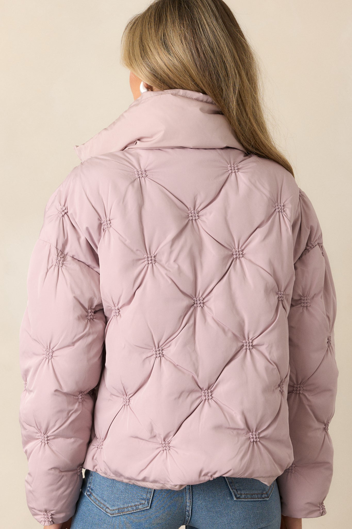 The back of the mauve puffer jacket, showcasing the tufted detailing, high collared neckline, and long sleeves.