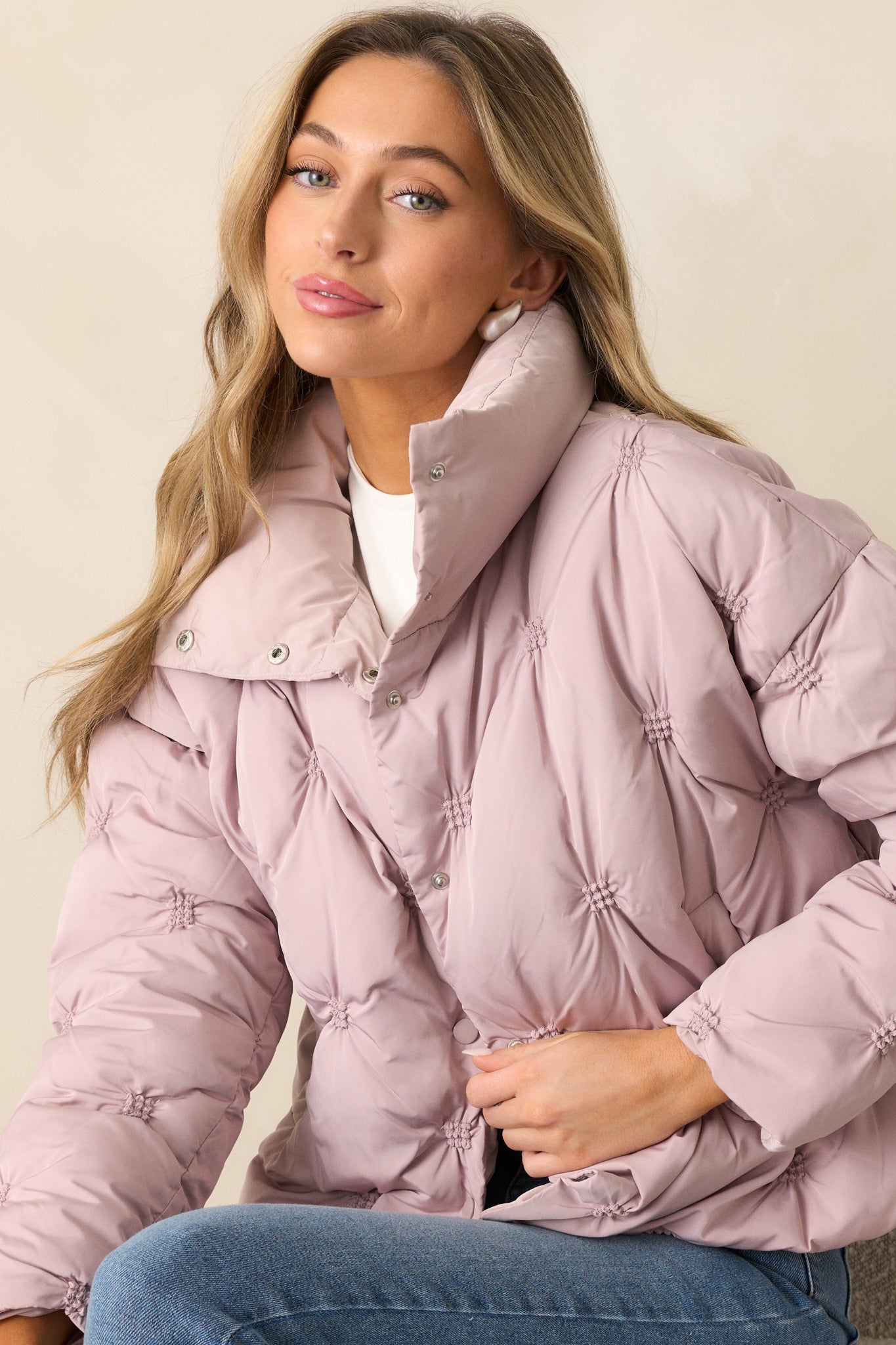 A side-angled view of the mauve puffer jacket, emphasizing the long sleeves and functional pockets.