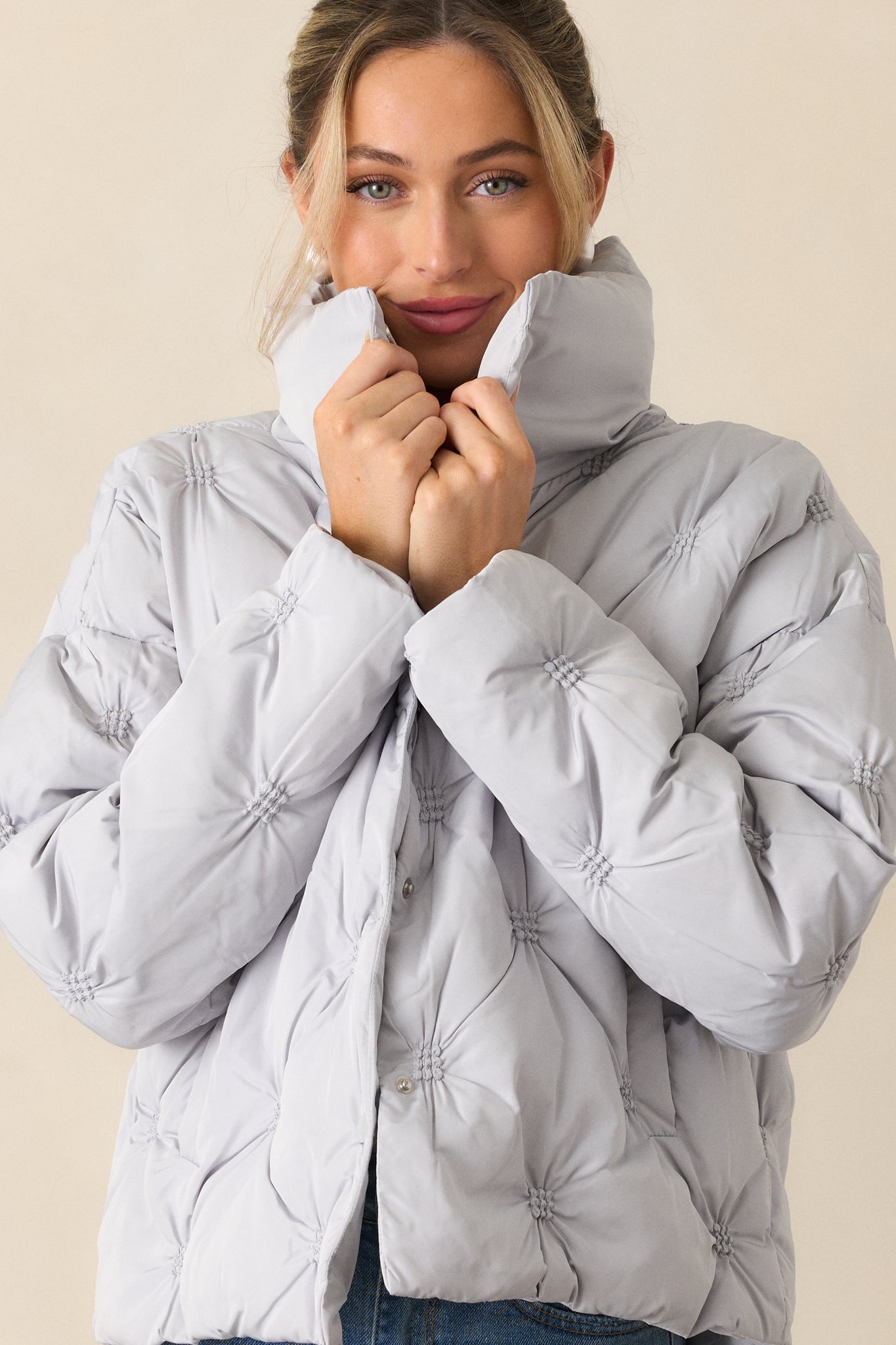 A close-up of the upper section of the jacket, focusing on the high collared neckline and snap button front.