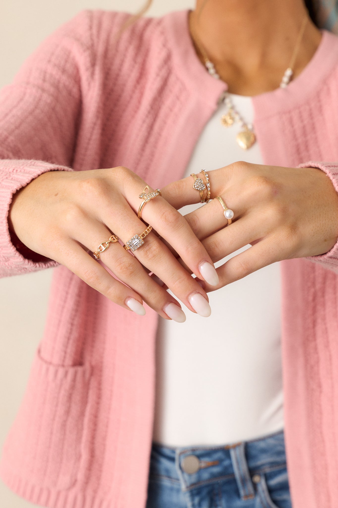 A detailed view of the gold rings showcasing a butterfly ring with rhinestones, a heart ring, and a statement square rhinestone ring.