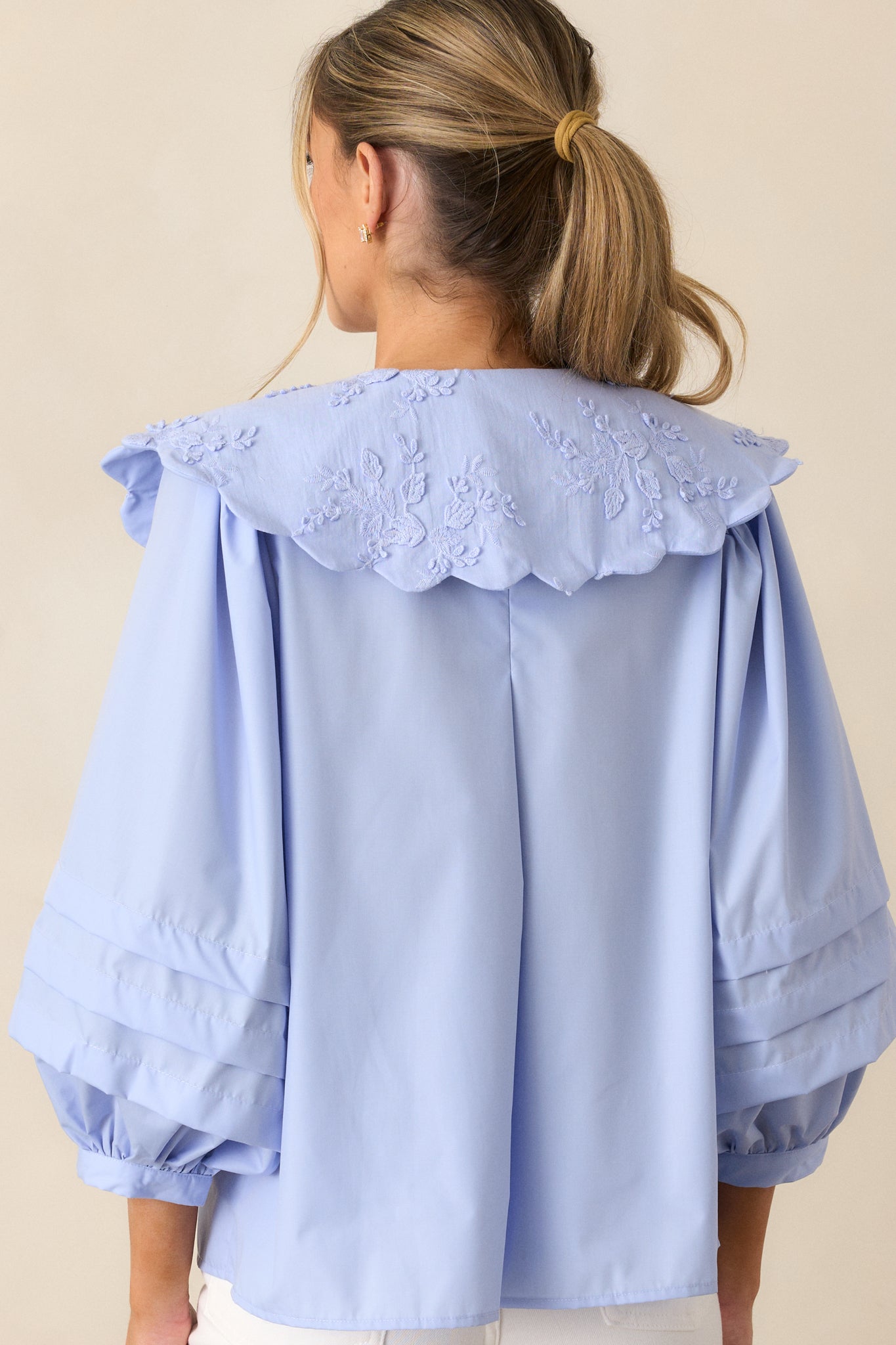 A back view of the sky blue blouse, focusing on the smooth fabric and the long puff sleeves with pleating at the shoulder area.