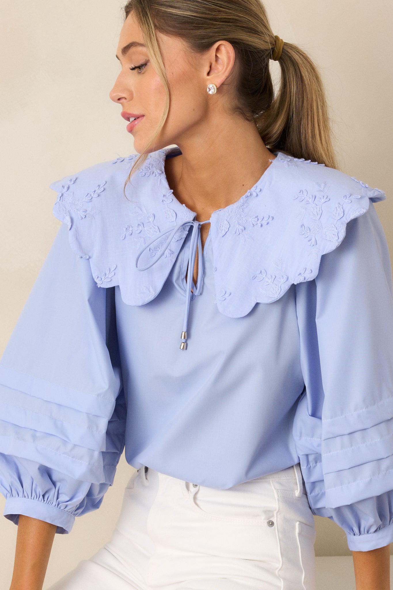 A cropped shot focusing on the top half of the blouse, highlighting the large scalloped collar with floral embroidery and the self-tie keyhole detail.