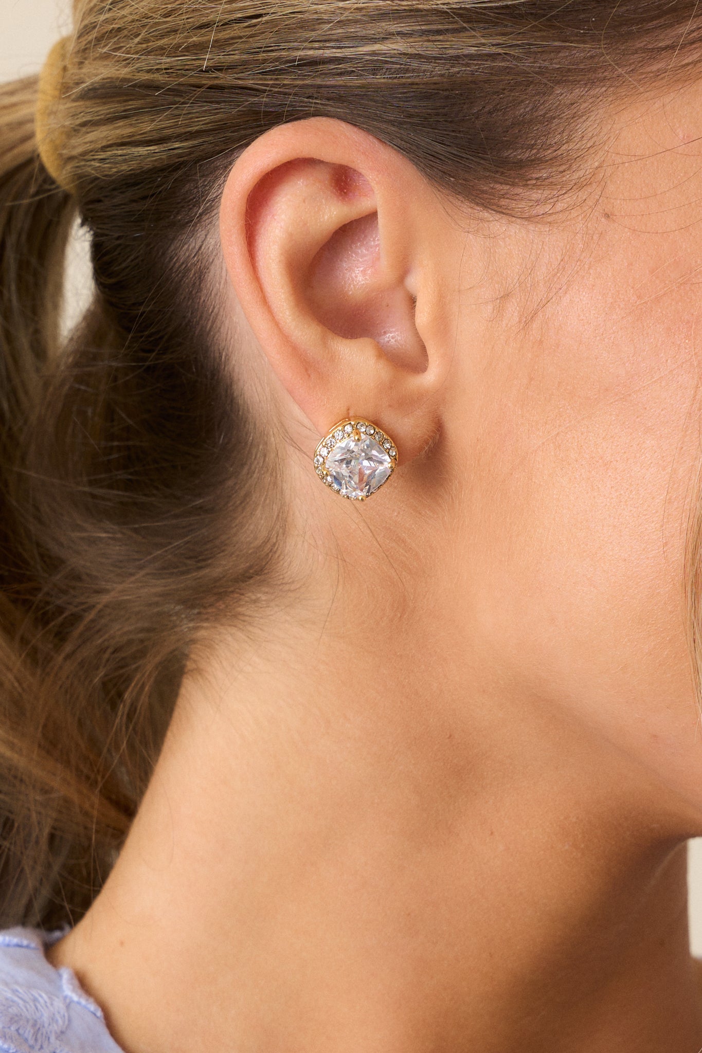 An extreme close-up of the gold stud earrings, highlighting the large central rhinestone, the delicate border of smaller rhinestones, and the smooth gold hardware and secure back postings.