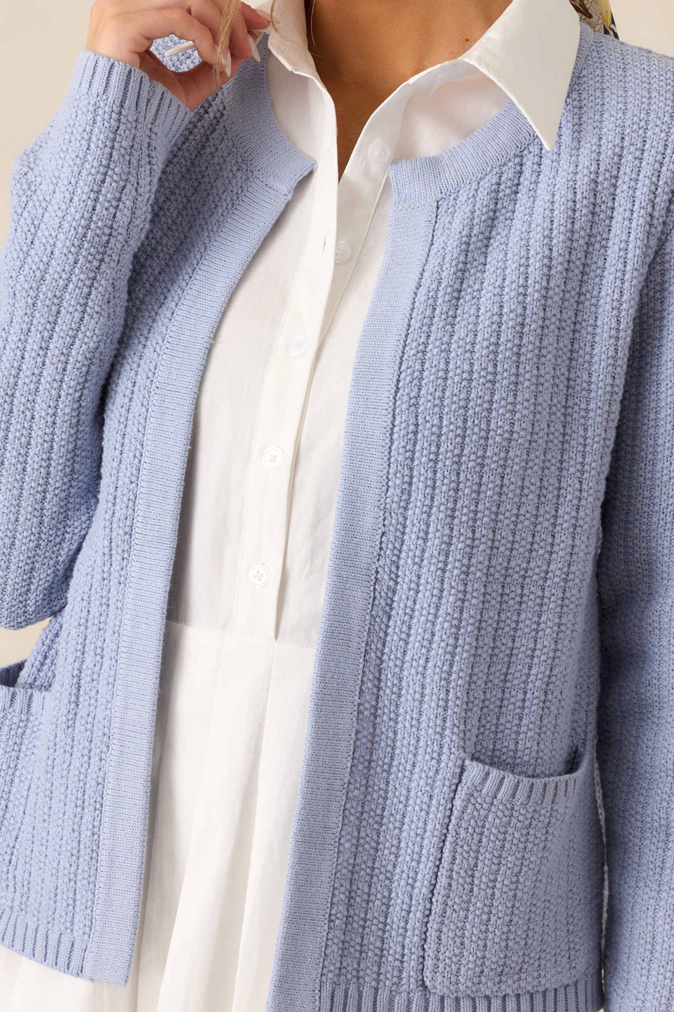 Close-up of the blue cardigan fabric texture, emphasizing the intricate knit design.