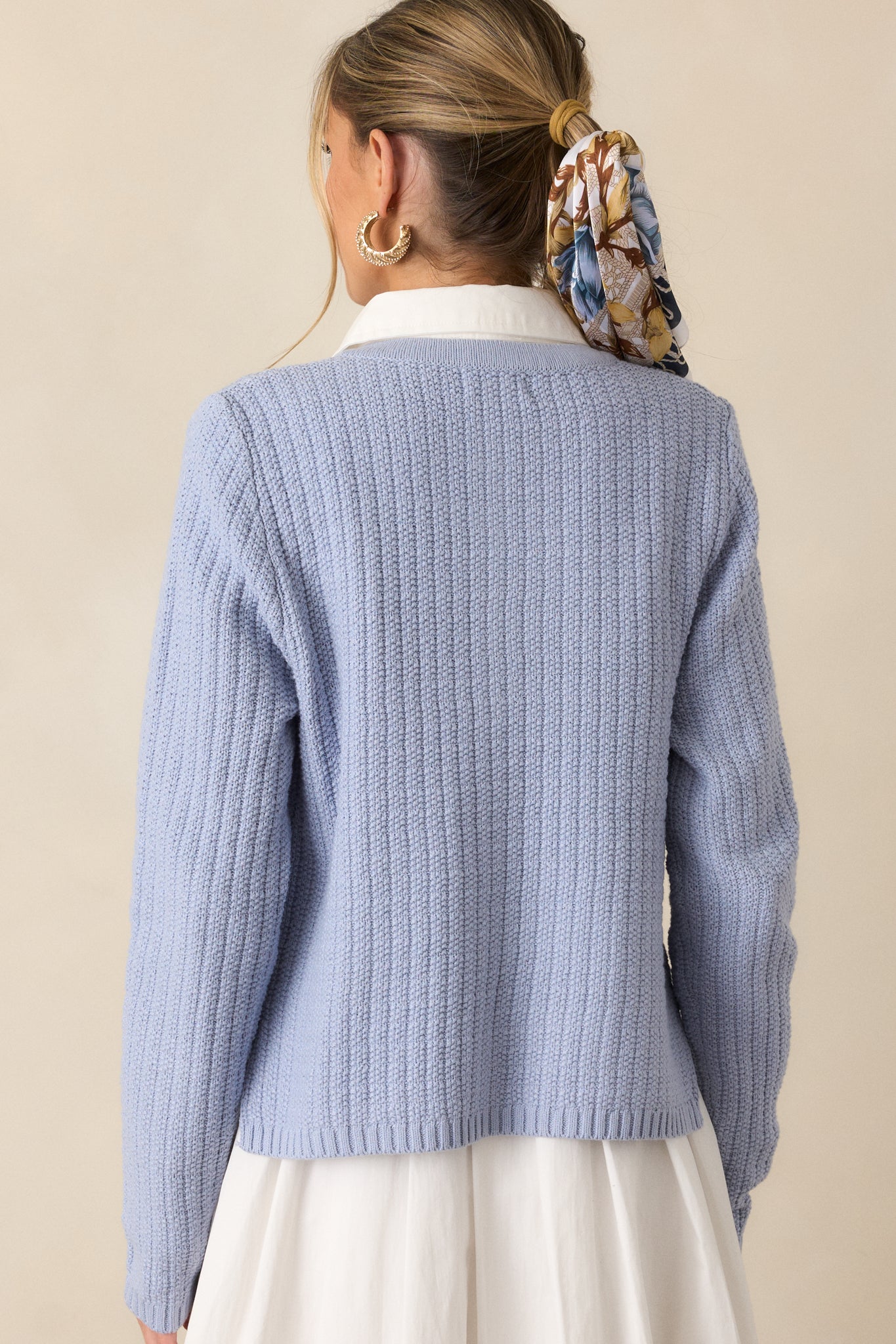 Rear view of the blue cardigan, showing the knit pattern and long-sleeved silhouette from the back.