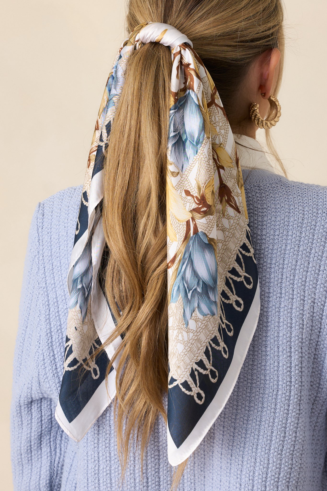 The navy satin scarf showcasing its gold and blue floral pattern and elegant navy trim, draped elegantly.