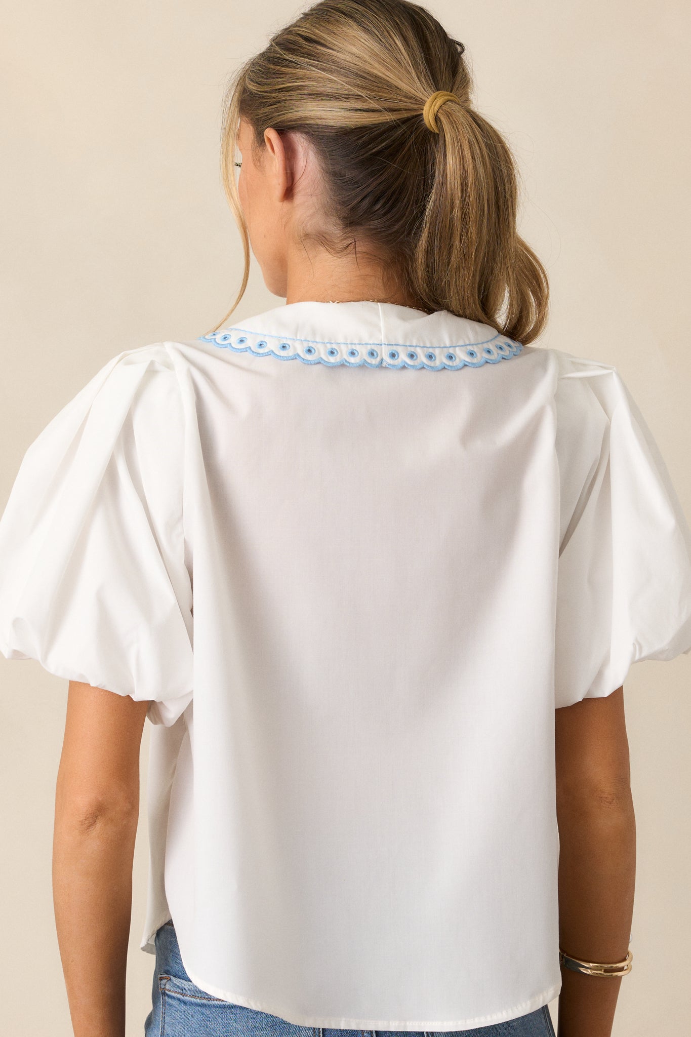 A view of the white top from behind, emphasizing the relaxed fit and flow of the fabric.