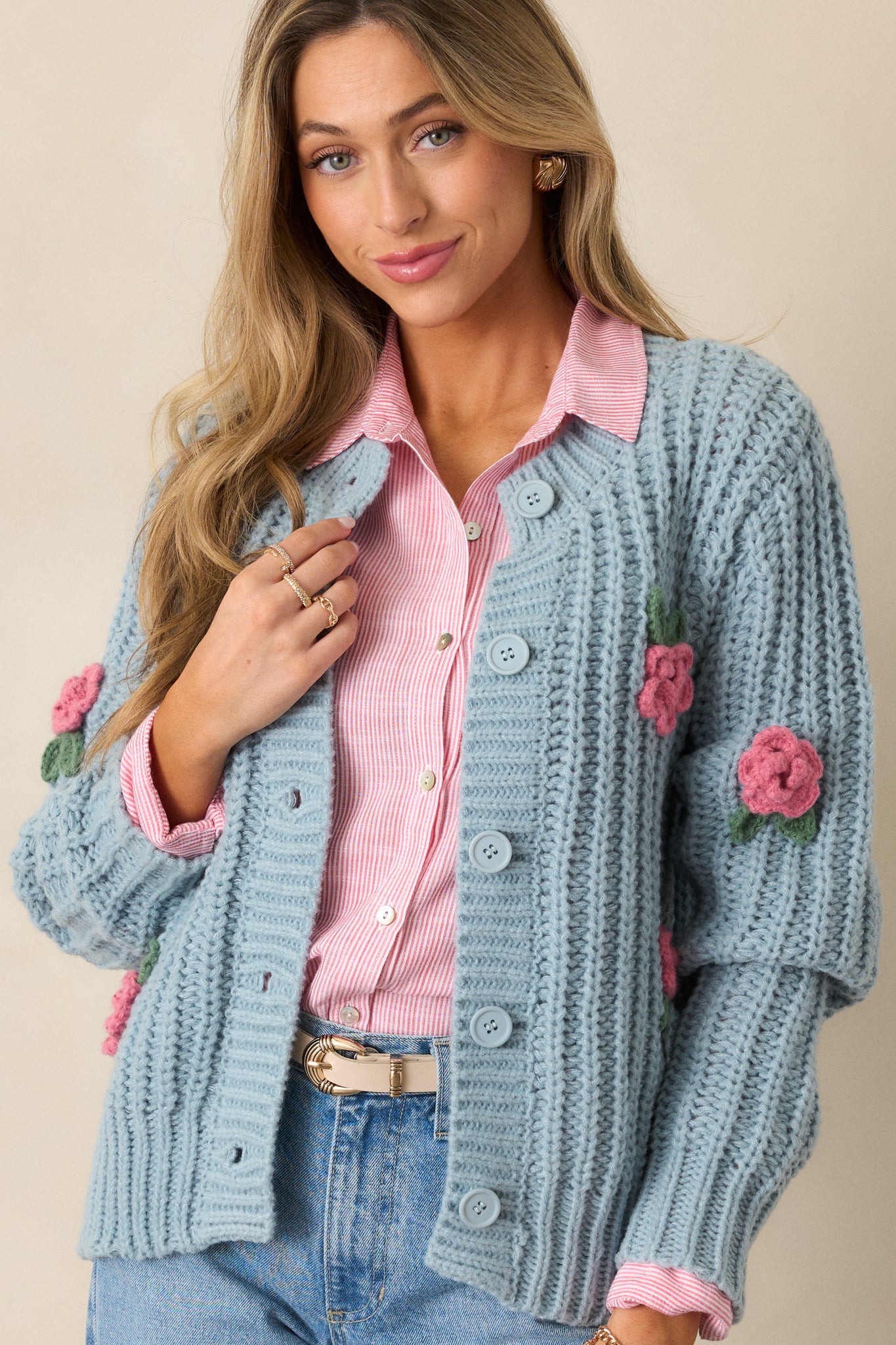 A cropped shot focusing on the upper half of the cardigan, featuring the rounded neckline, button front design, and the crochet rose detailing along the shoulder area.