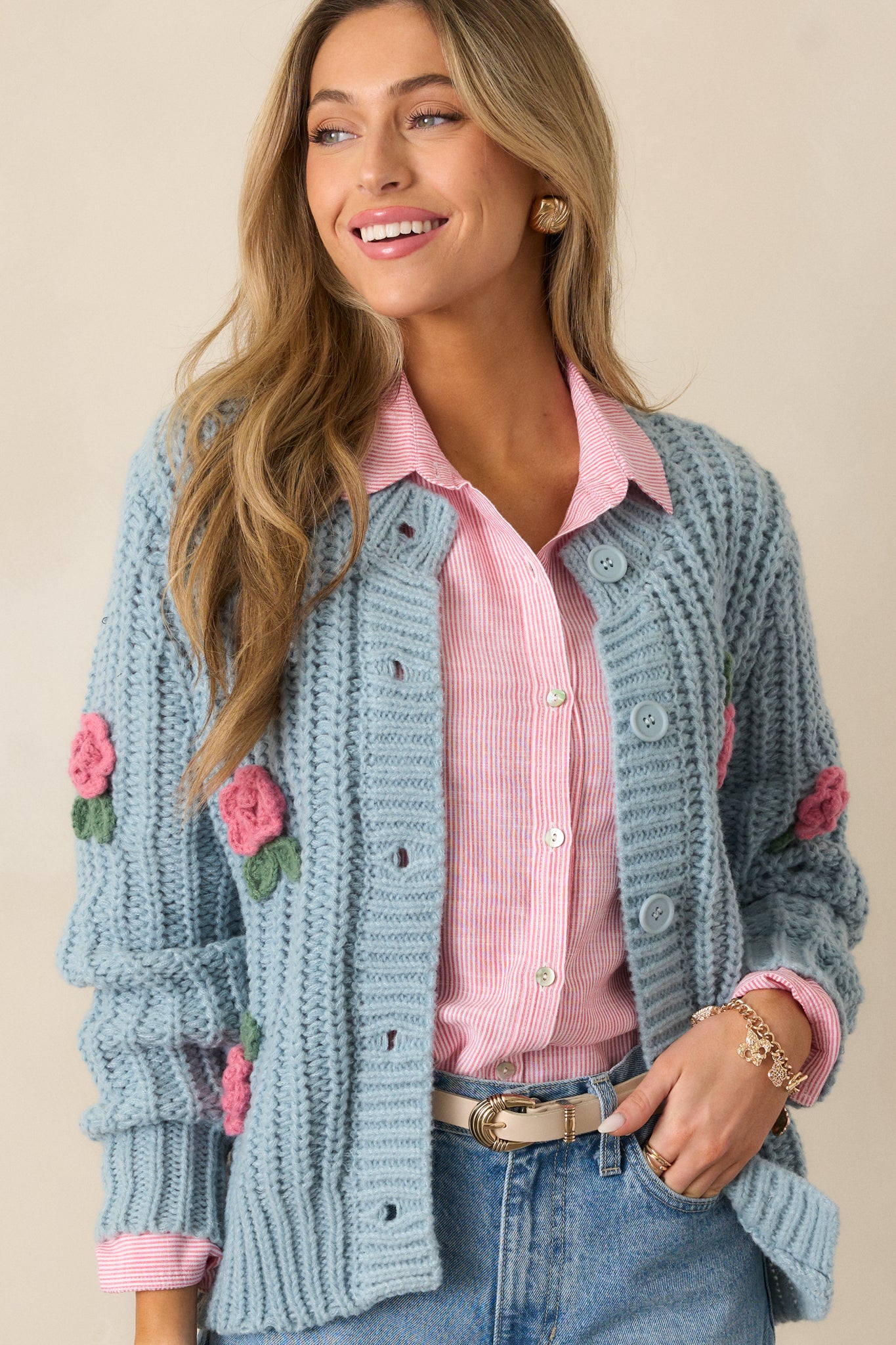 A close-up of the button front design and crochet rose detailing at the chest area, showcasing the craftsmanship and texture of the cardigan.