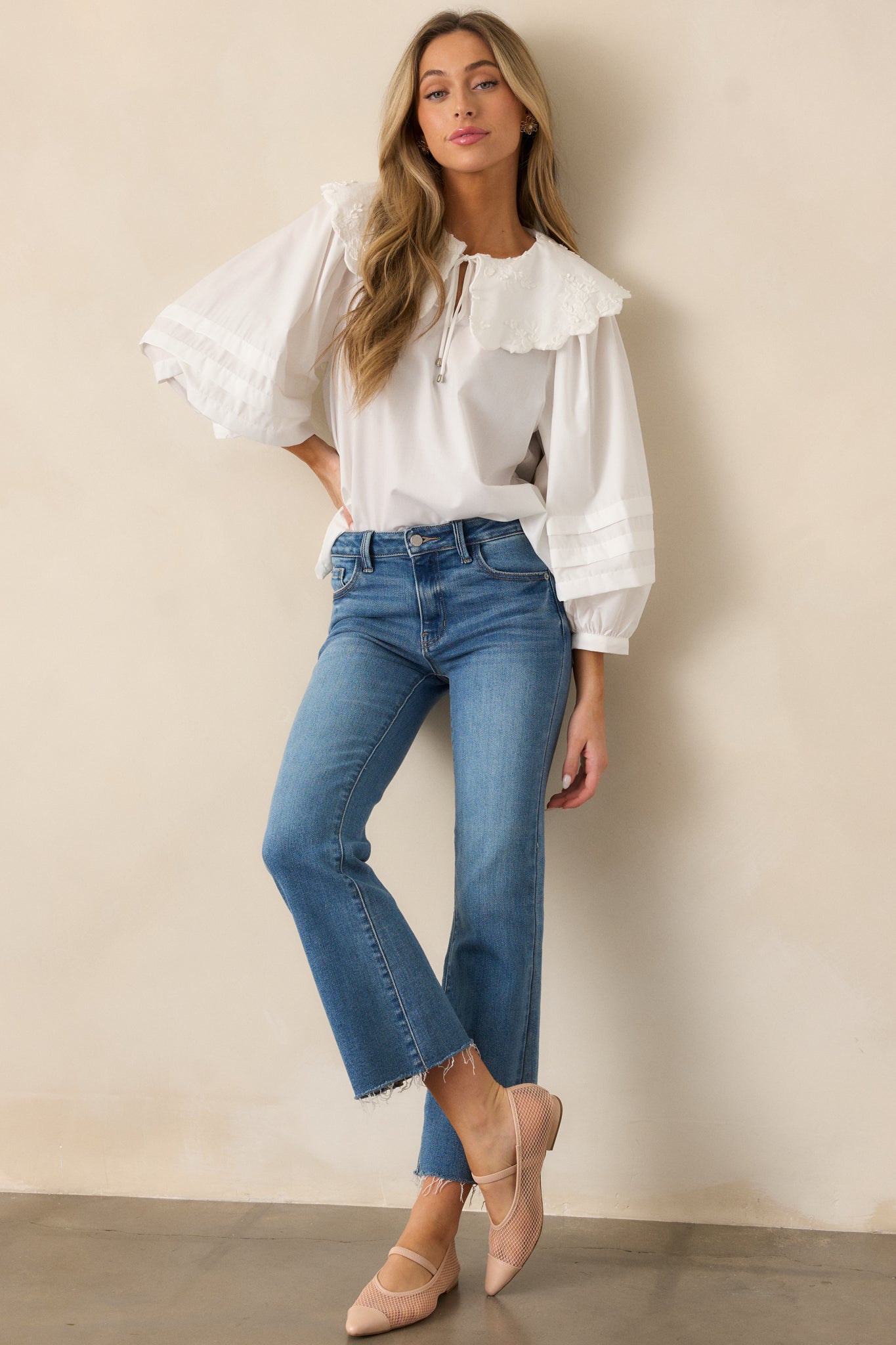 A front-facing shot of the ivory blouse, highlighting the large scalloped collar, intricate floral embroidery, and the self-tie keyhole closure, with puffed sleeves and pleated detailing extending to the wrists.