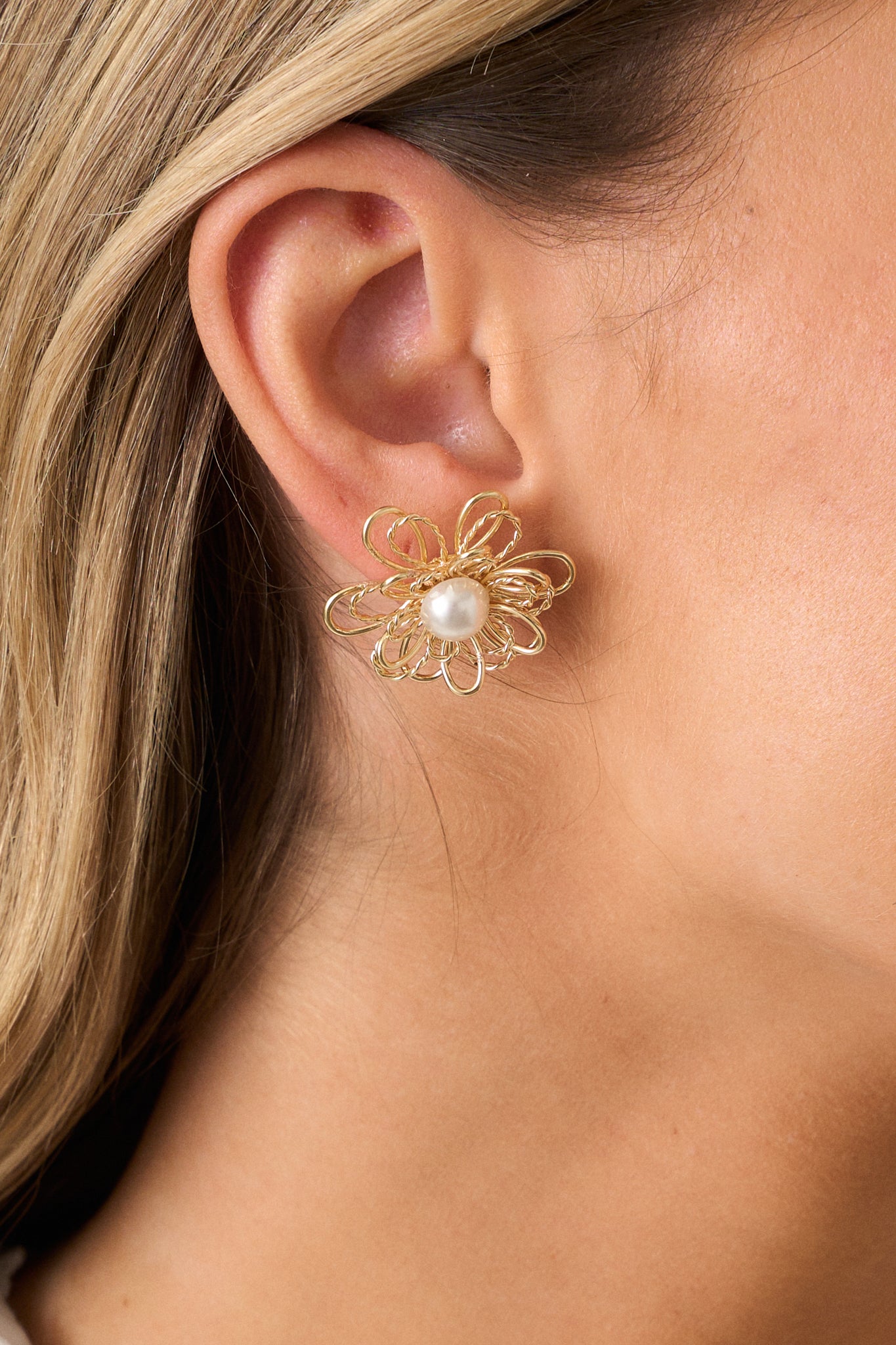 A detailed close-up of the gold floral earrings, highlighting the faux pearl centerpiece surrounded by delicate gold petals, and the smooth gold hardware with secure back postings.