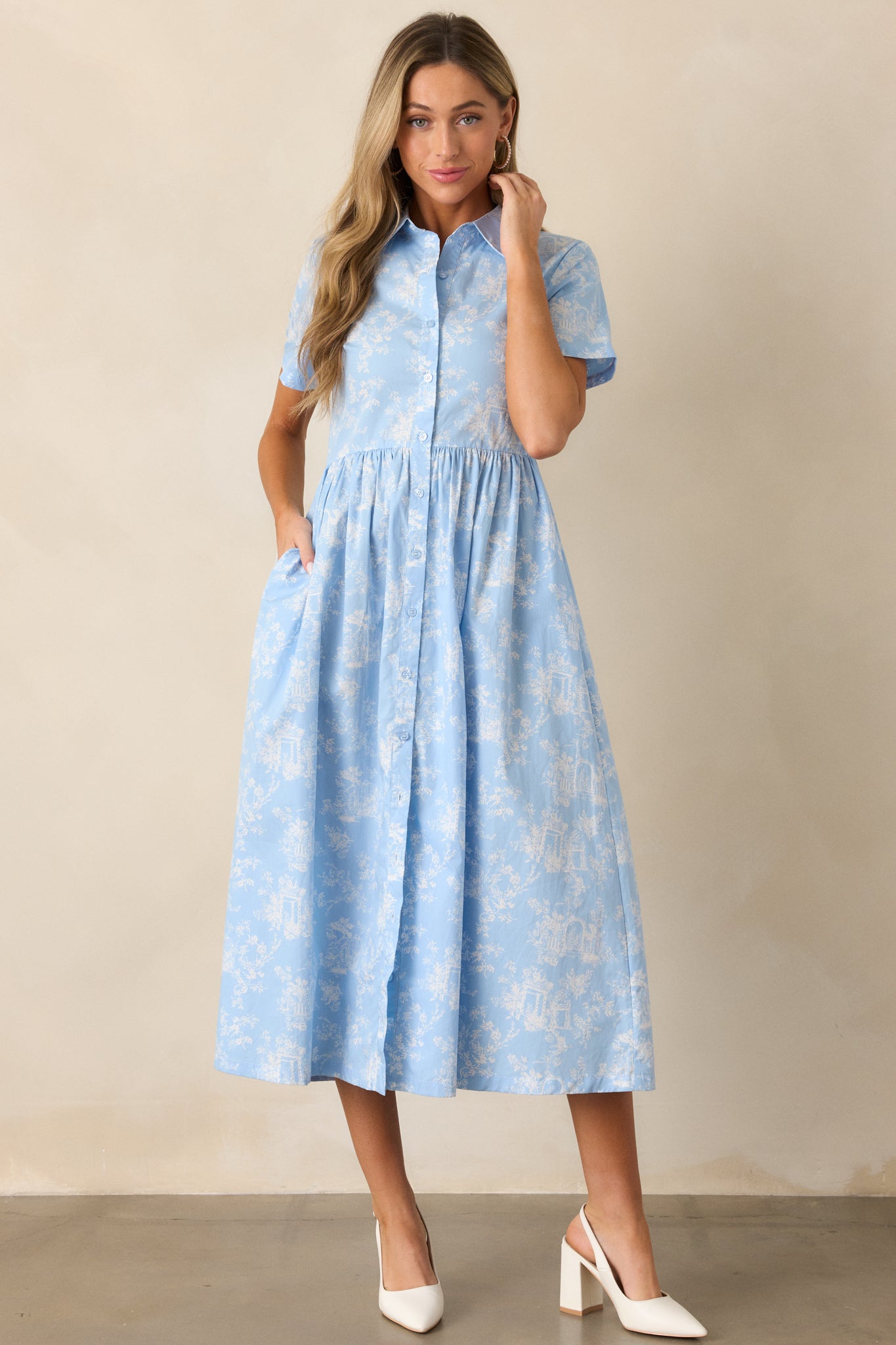 A light blue maxi dress with a collared neckline, a button front, and a flowing silhouette featuring a toile pattern.