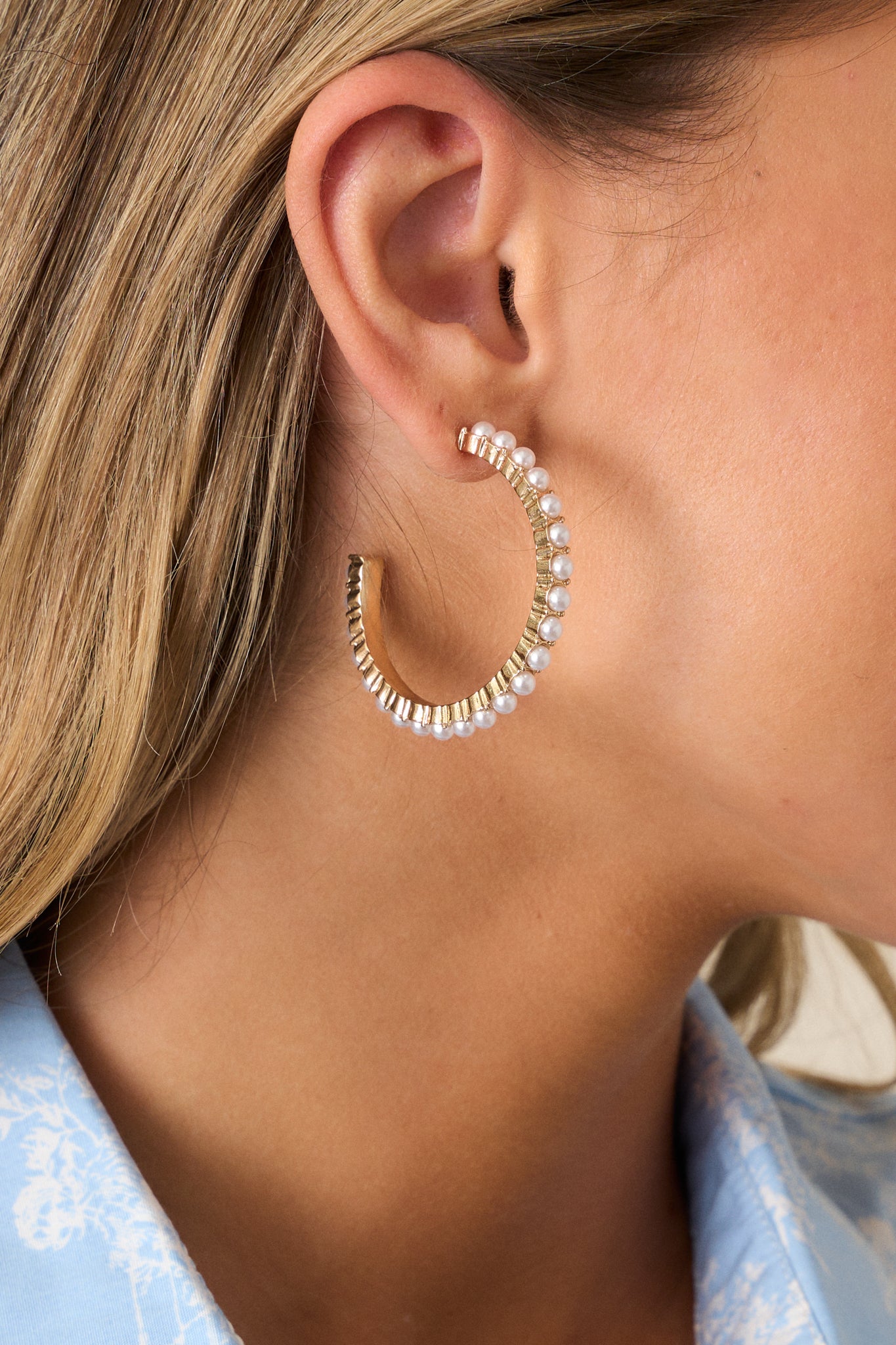 A close-up of the gold and ivory hoop earrings showcasing the textured gold hardware and precise pearl arrangement.