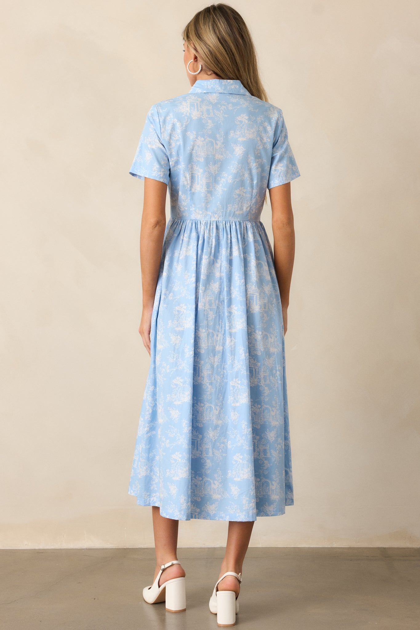 A view of the light blue maxi dress from behind, accentuating the flowing silhouette and continuous toile pattern.