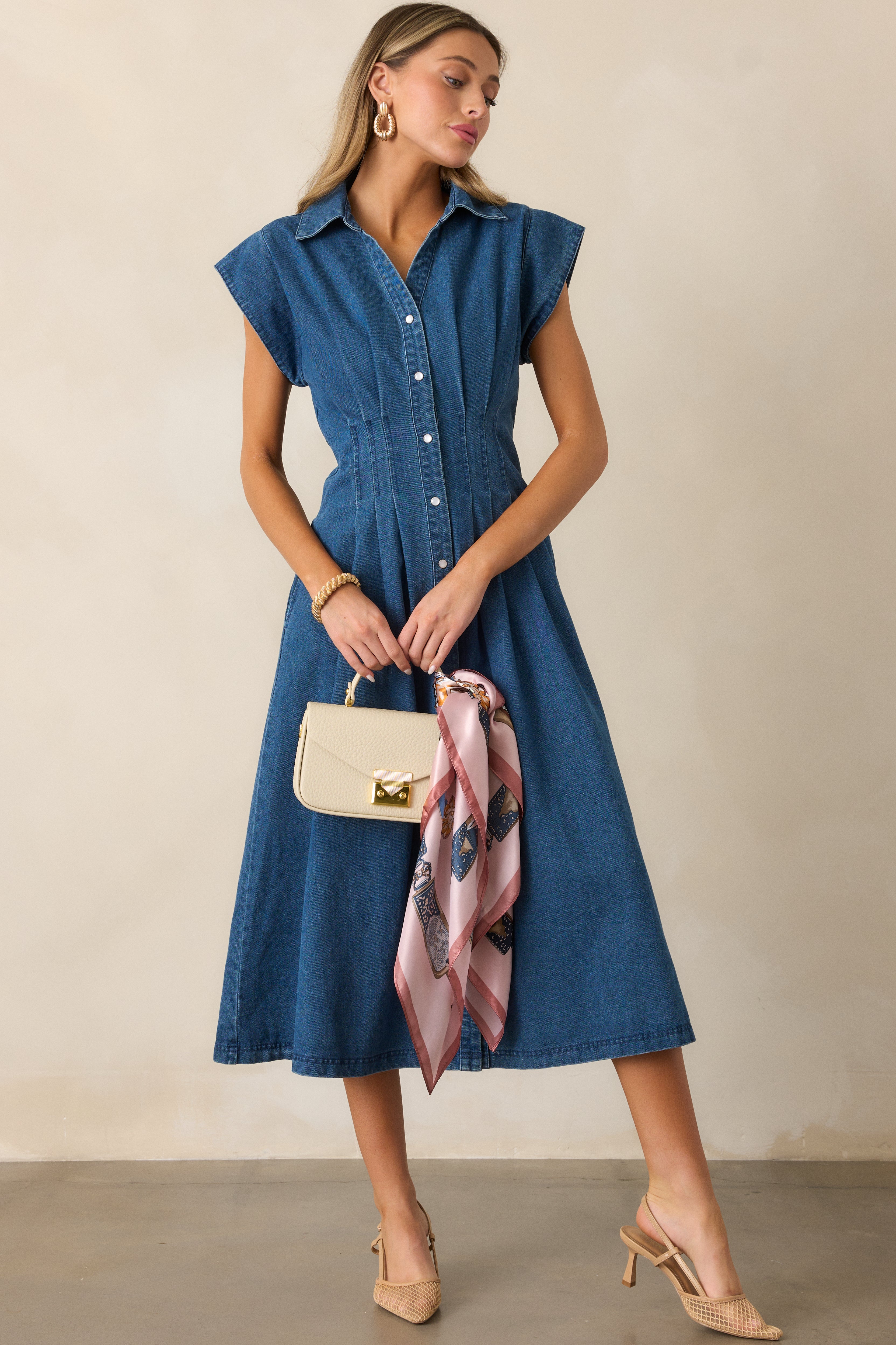 Dark wash dress showcasing a pleated waist, cap sleeves, and functional pockets, with a full view of the button-down front design.