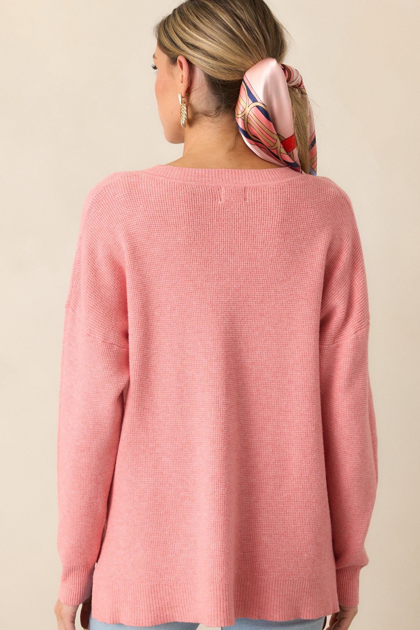 The back view of the rose sweater, emphasizing its relaxed fit and split hem bottom for an effortlessly chic look.