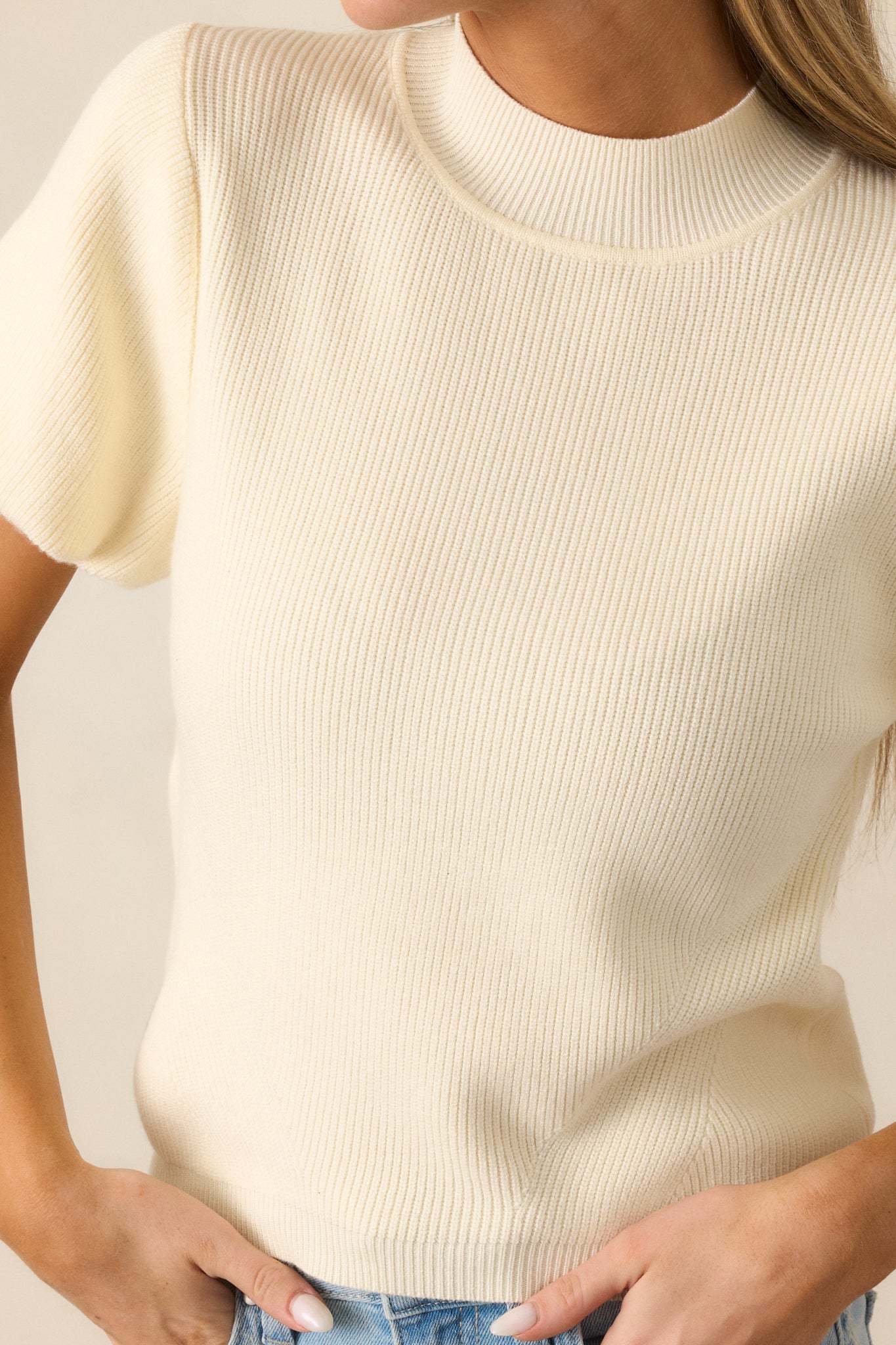 A close-up of the knit texture on the ivory top, showing off the mock neckline and the gentle puff of the short sleeves