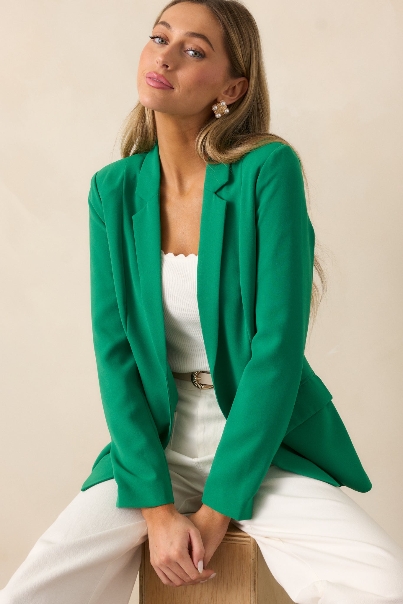 Close focus on the green blazer’s notched lapel collar and open front, highlighting the structured shoulder padding.