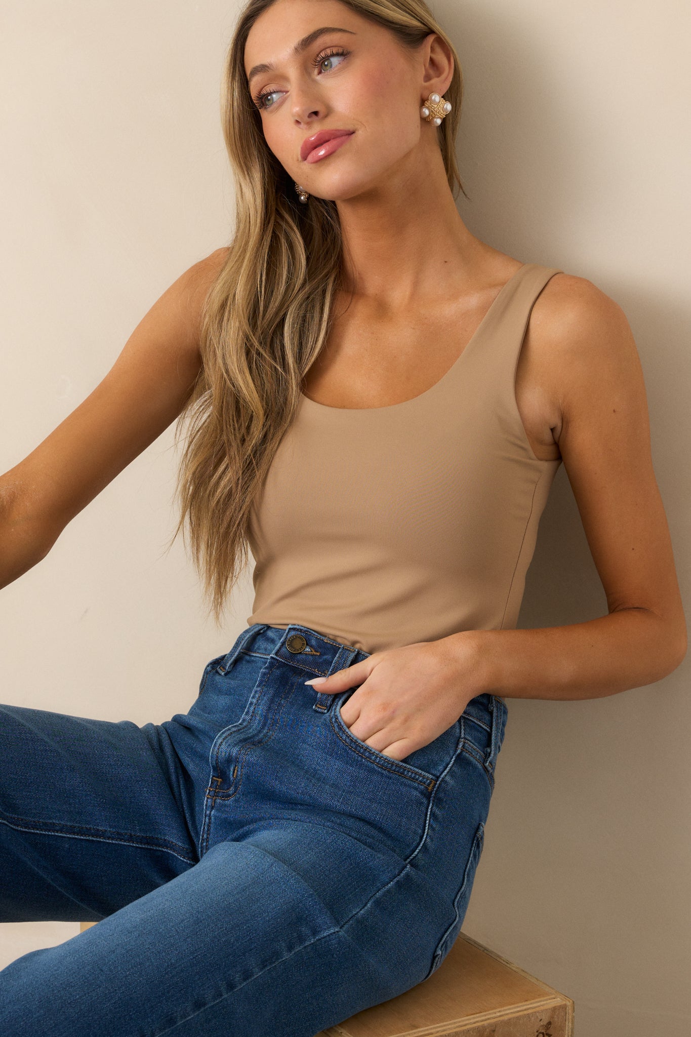 Cropped view of the upper section of the tan bodysuit focusing on the scoop neckline and seamless finish.