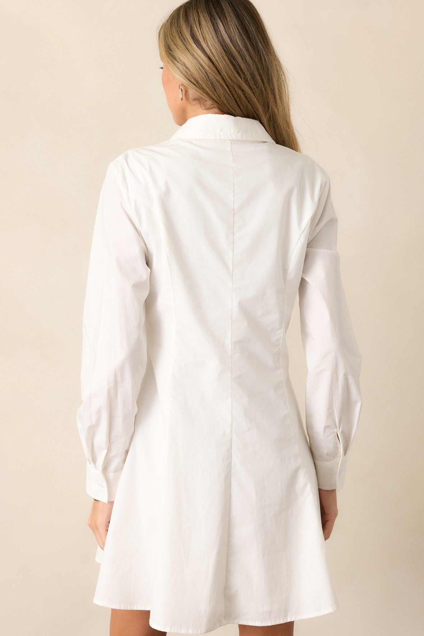 The back view of the ivory mini dress, featuring its clean lines, long sleeves, and simple, elegant structure.