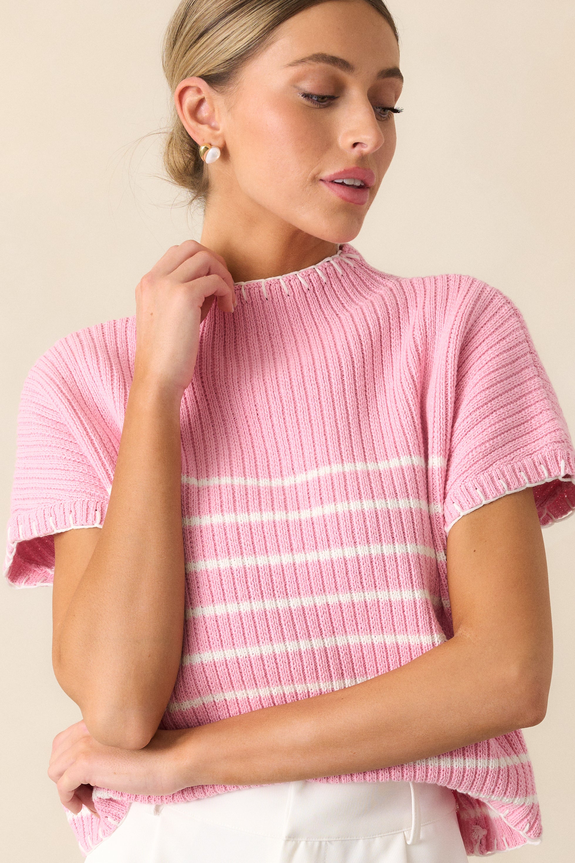 A cropped view of the pink sweater, highlighting the white stripe detailing at the bust and the smooth fabric.