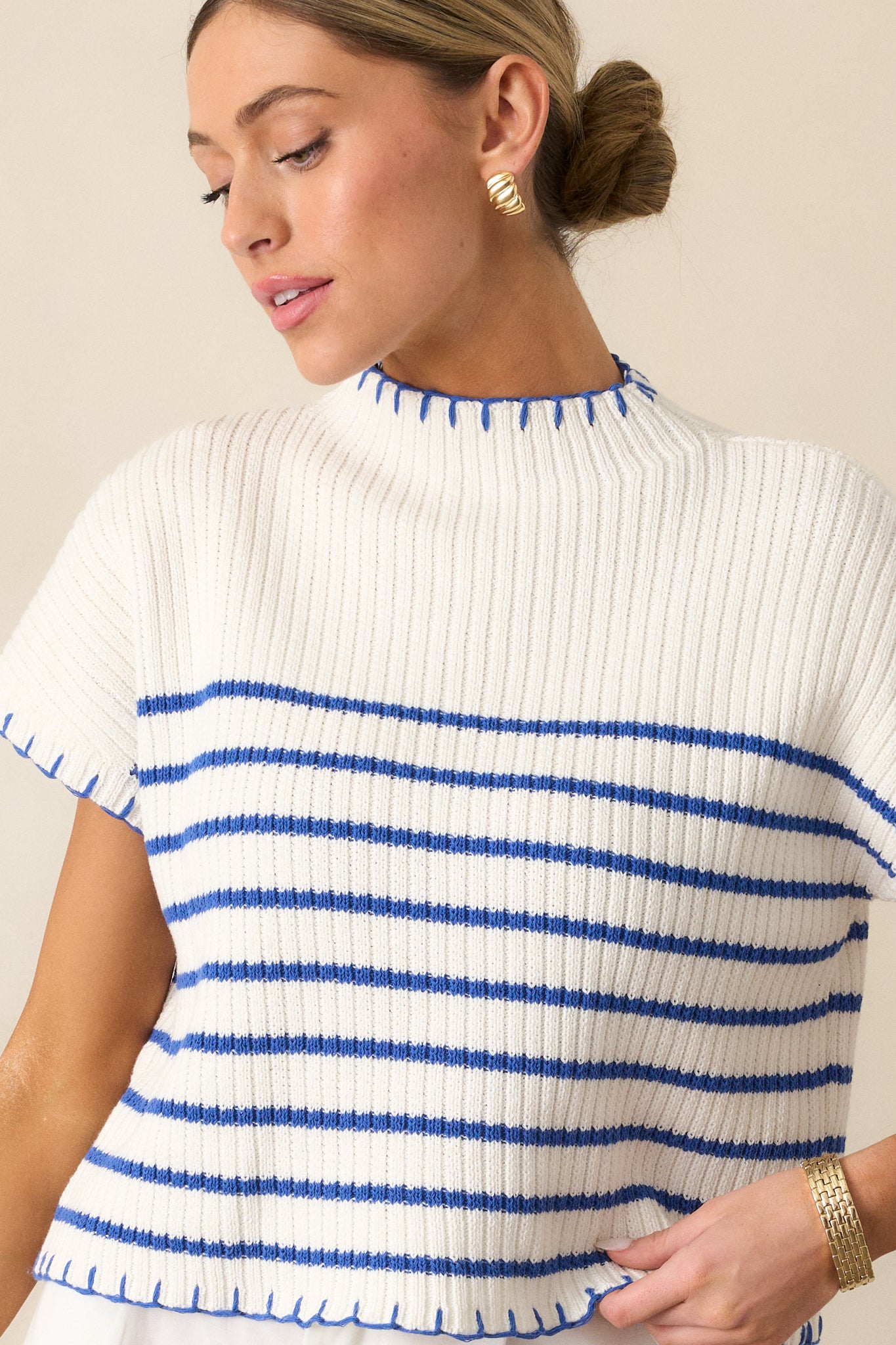 A cropped view of the white sweater, focusing on the blue whipstitch detailing at the hem for a touch of texture.