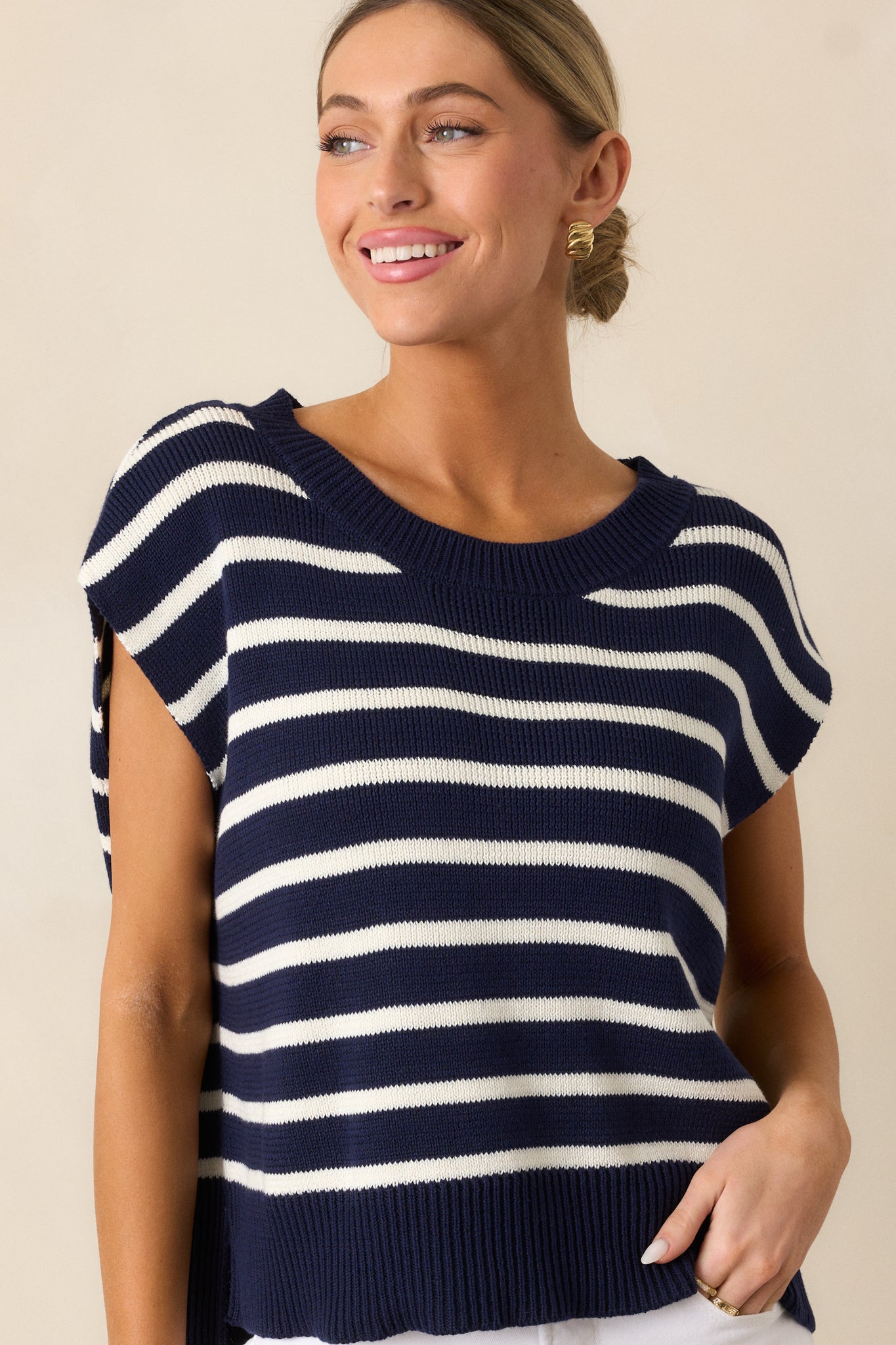  Focused view of the split ribbed hemline on the navy sweater top, with horizontal stripes continuing across the design.