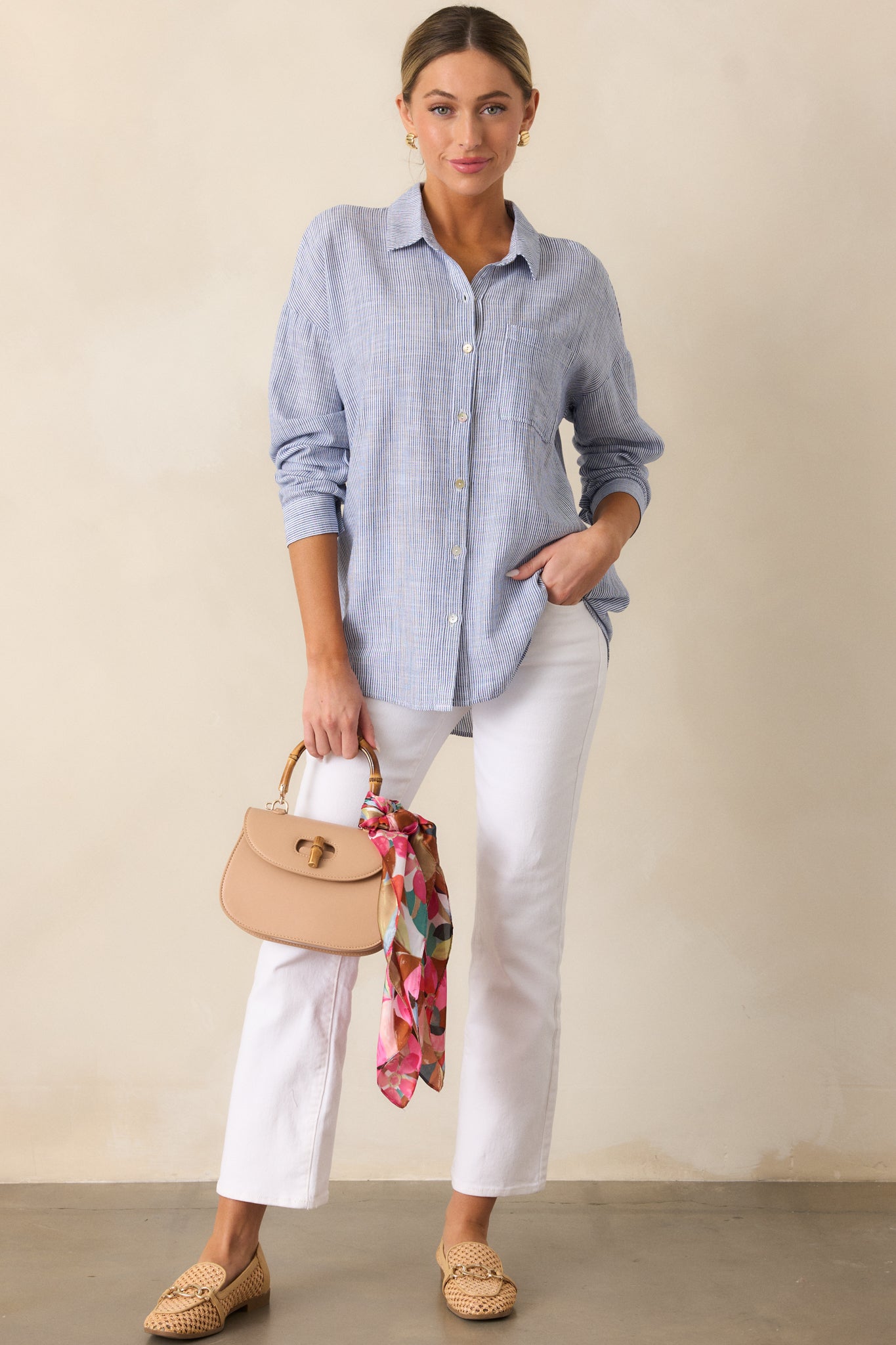 A complete look featuring the blue top with its button front design and collared neckline, focusing on the detailing of the blouse’s relaxed fit.