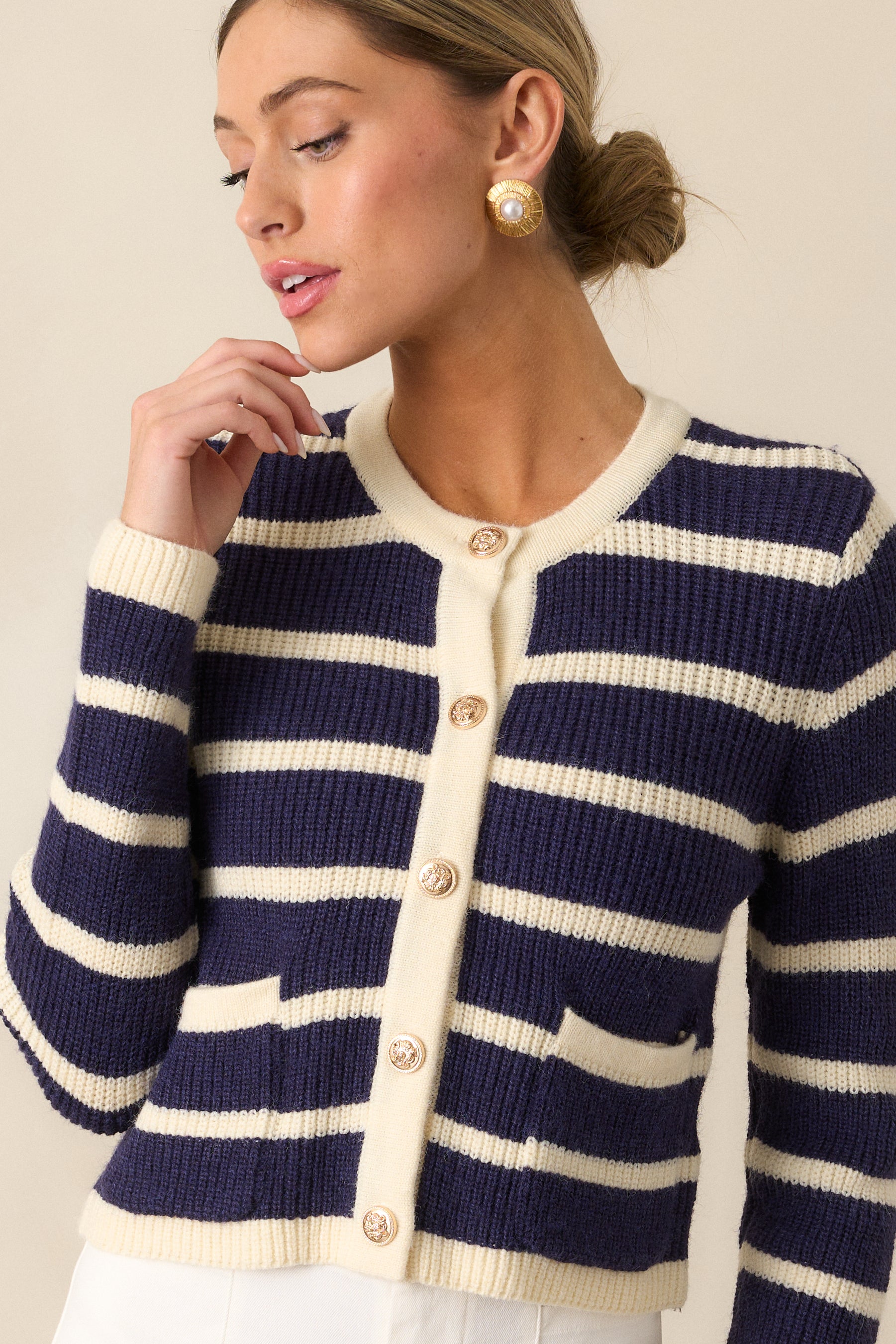 A cropped view of the navy stripe cardigan, focusing on one functional patch pocket with its striped detailing.