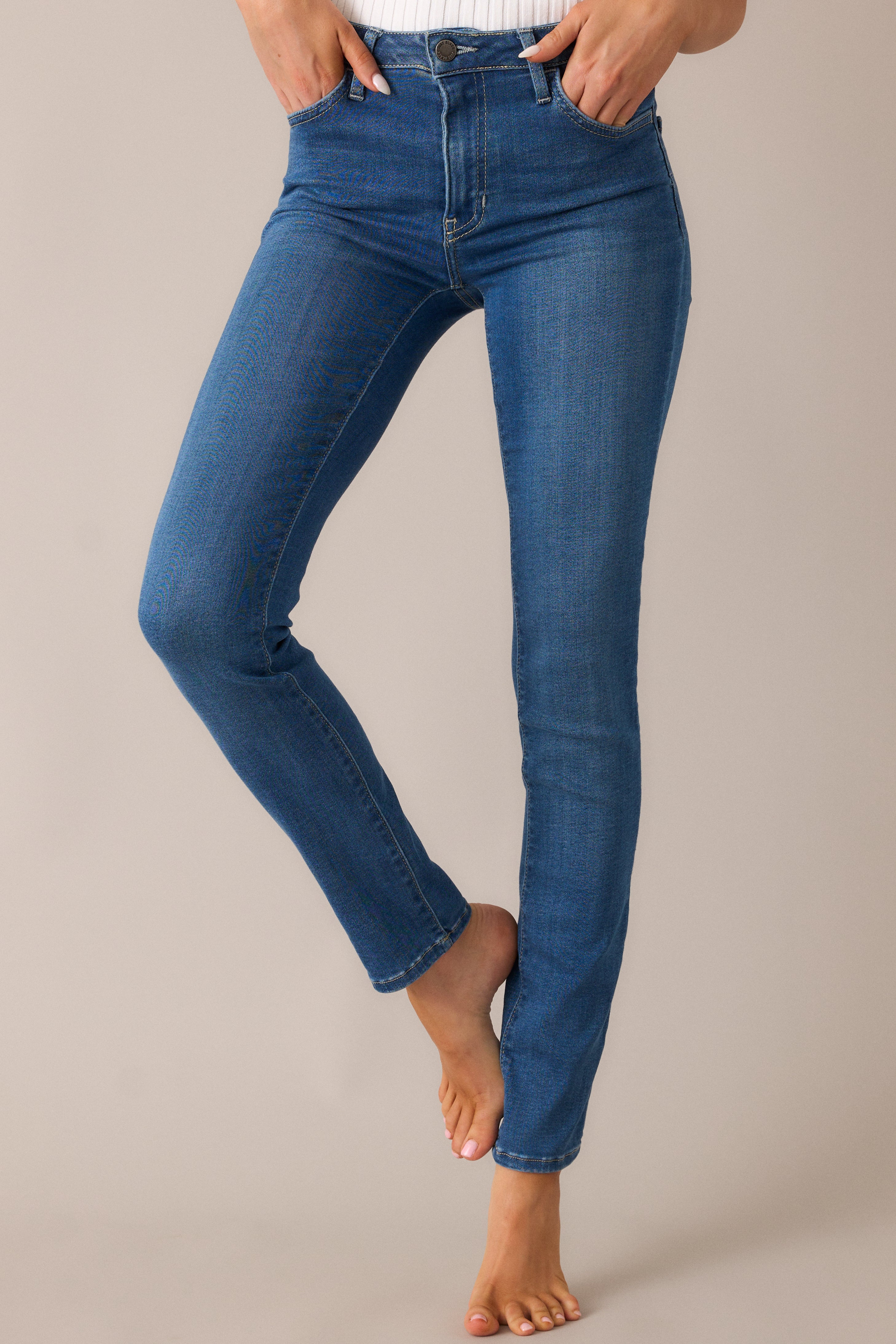 Close-up of the high-waist design and functional pockets, showcasing the chic, fitted look of these medium-wash skinny jeans with a tailored finish.