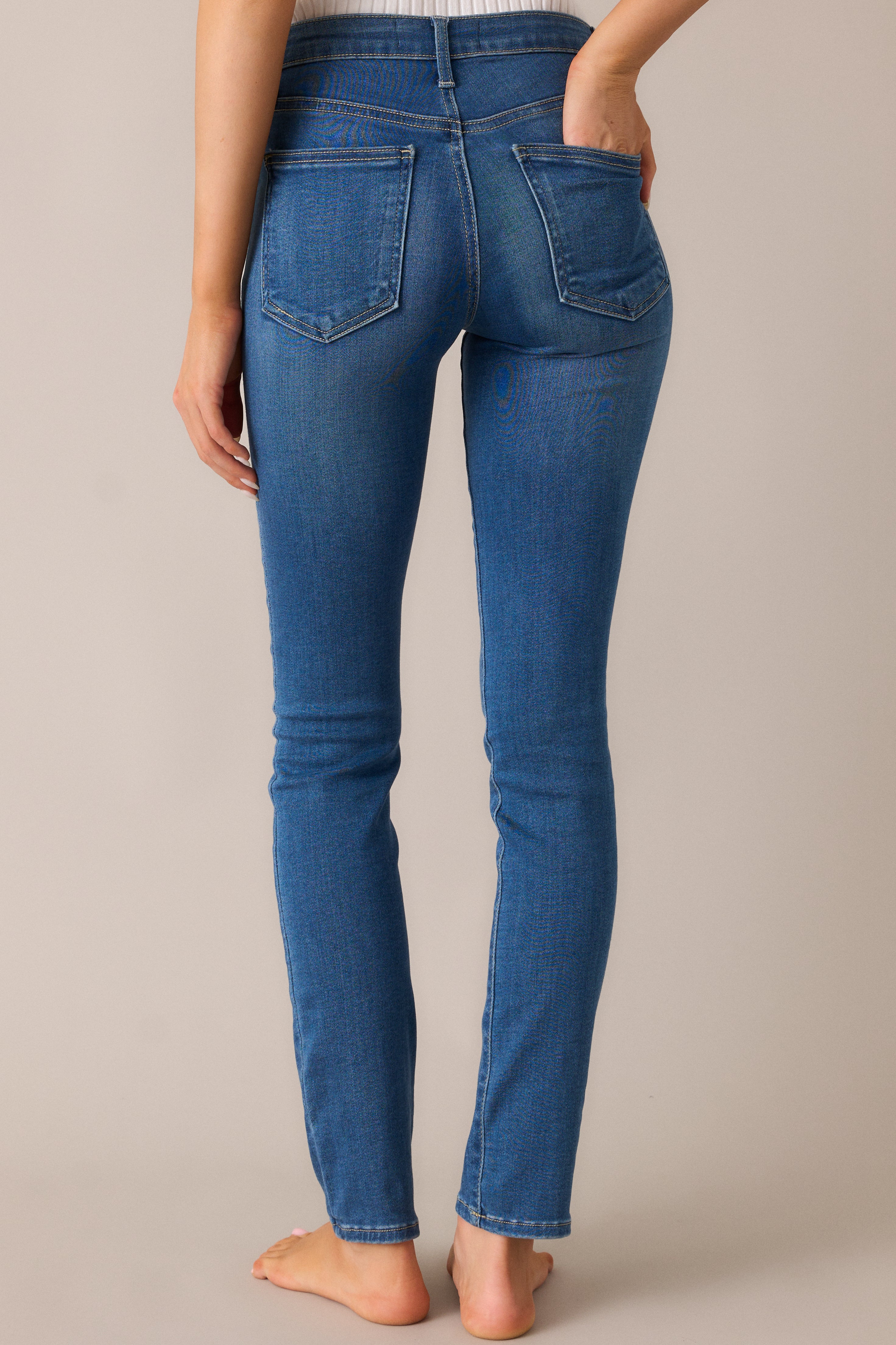 The medium-wash skinny jeans from the back, highlighting the flattering high-waist design and functional pockets that create a polished, well-fitted look.