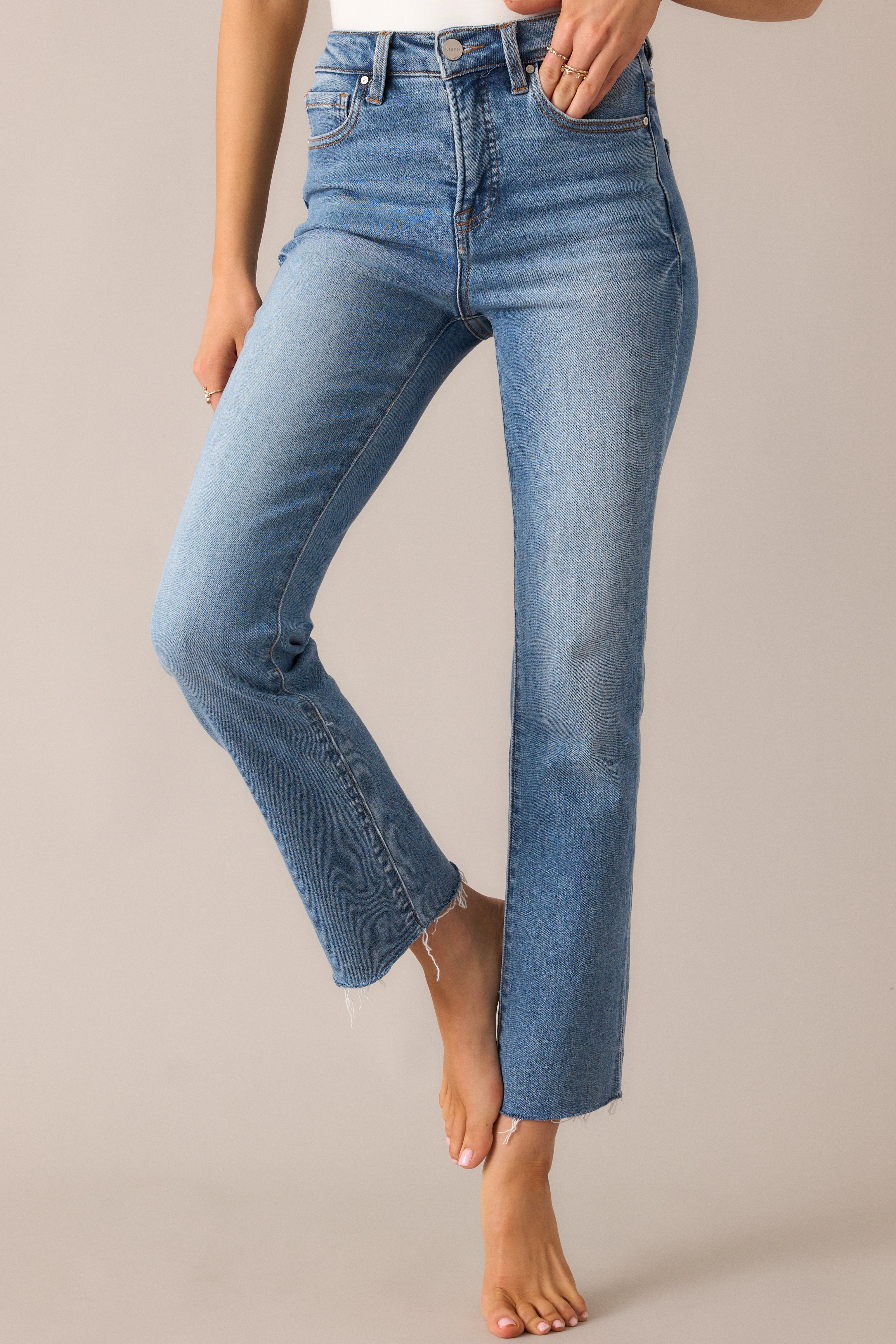 Detailed view of the zipper and button closure, showcasing the sturdy hardware and smooth fit of the medium-wash jeans with functional pockets.